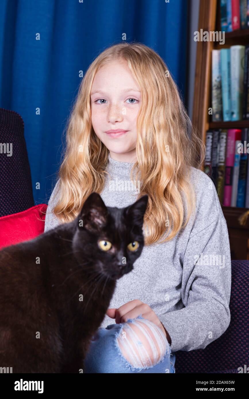 12yearold sitting at home with her cat for company. Focus on girl