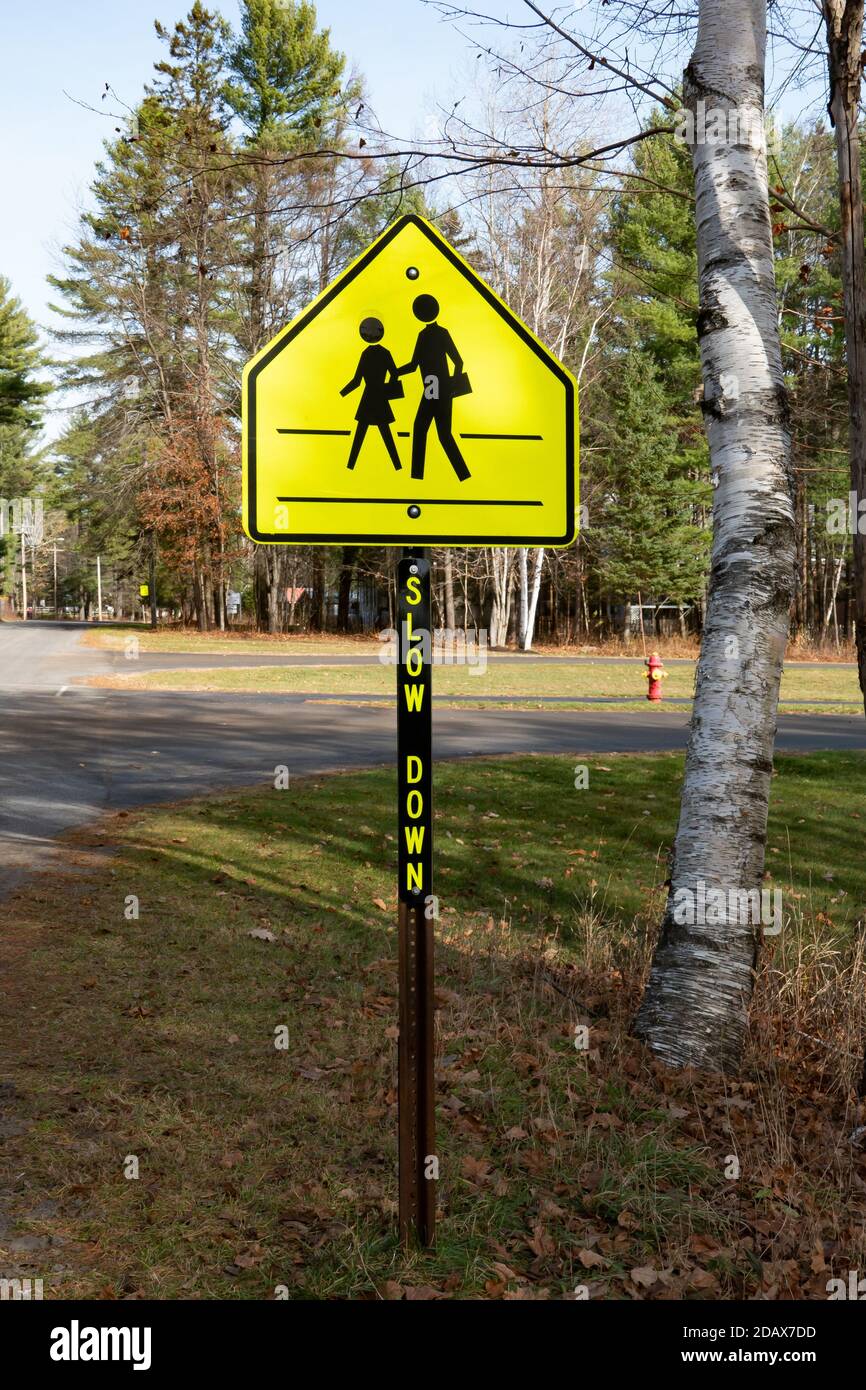 A bright yellow school crossing sign warning motorists to slow down. Stock Photo