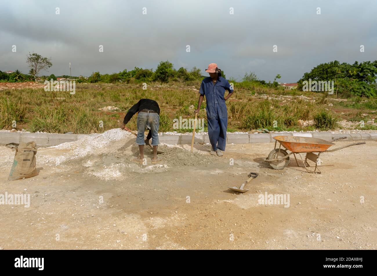 Standing And Looking At A Worker Mixing Mortar Stock Photo