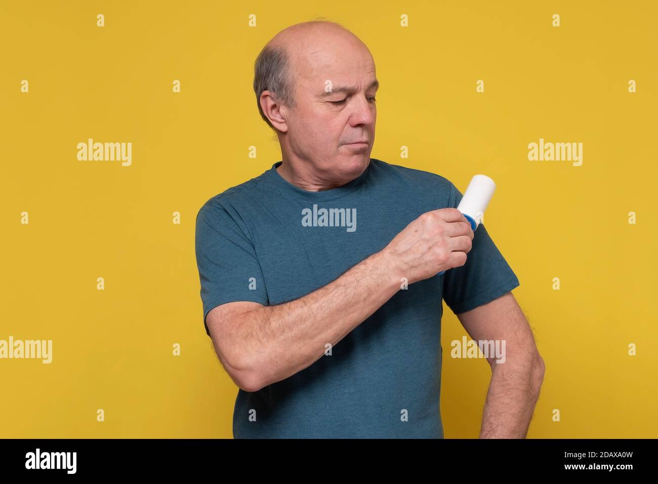 Senior caucasian man holding a hair removal roller cleaning his clothes. Stock Photo