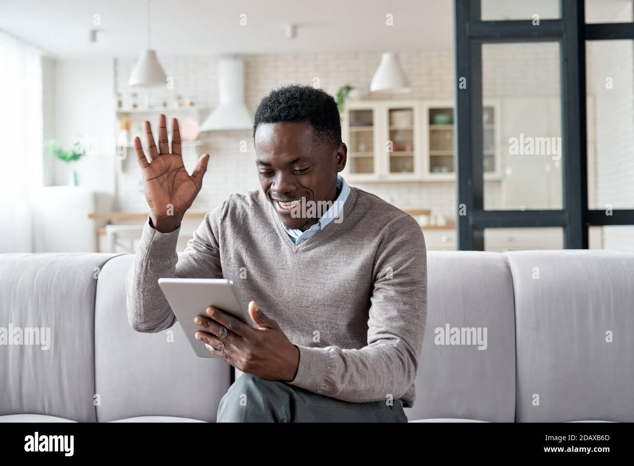 African american man waving hand video calling on digital tablet at home. Stock Photo