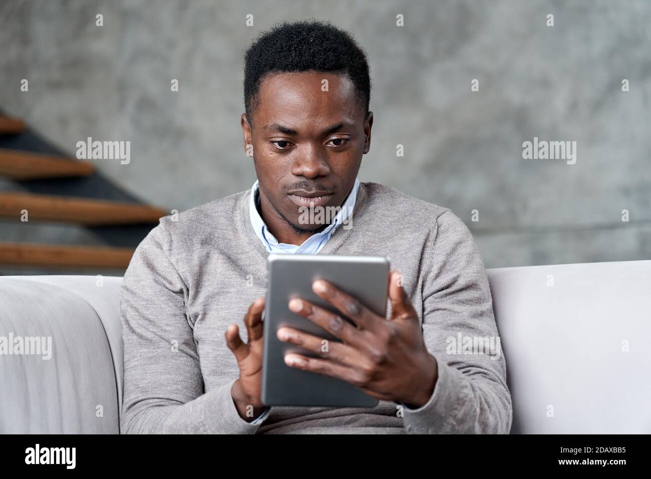Young adult african man using digital tablet apps on computer at home. Stock Photo