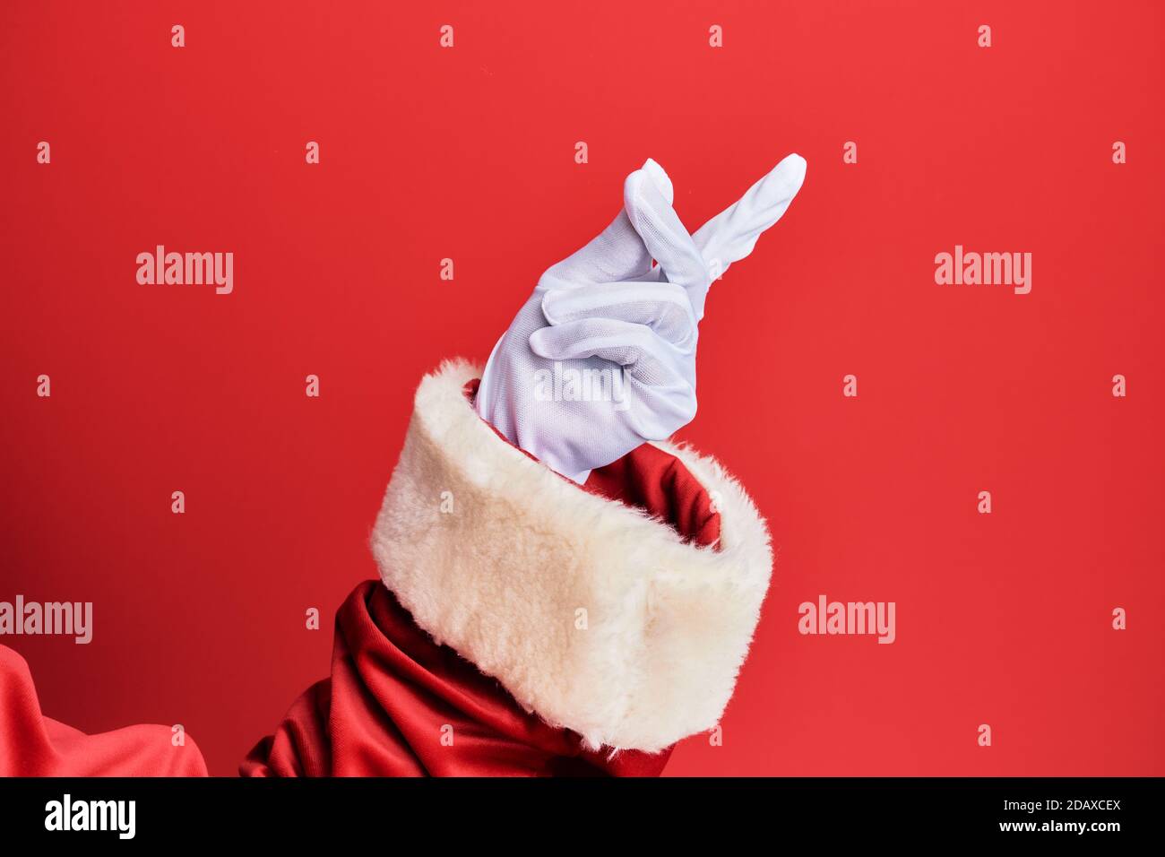 Hand of a man wearing santa claus costume and gloves over red background snapping fingers for success, easy and click symbol gesture with hand Stock Photo