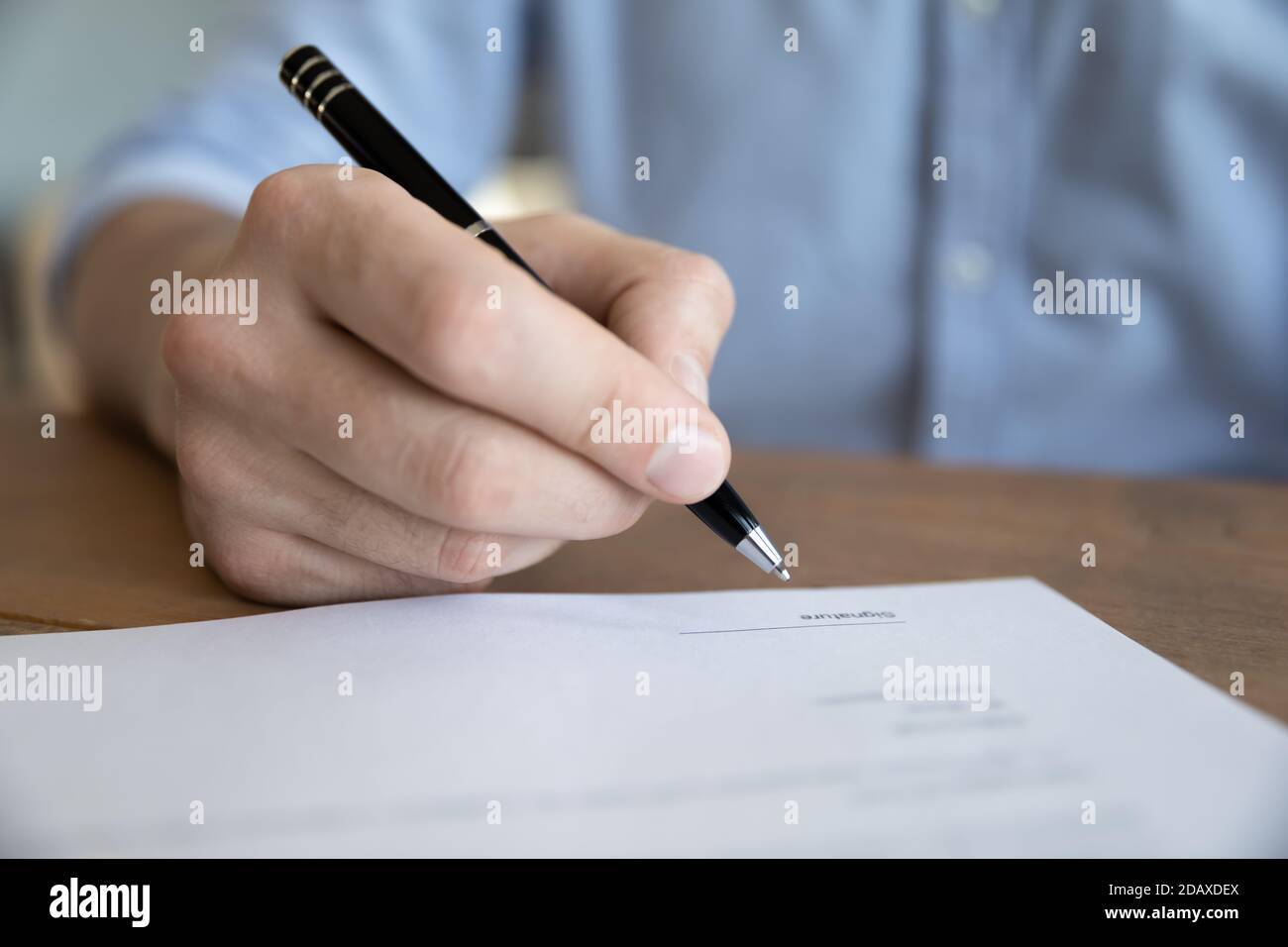 Close up male hand holding pen signing insurance agreement Stock Photo