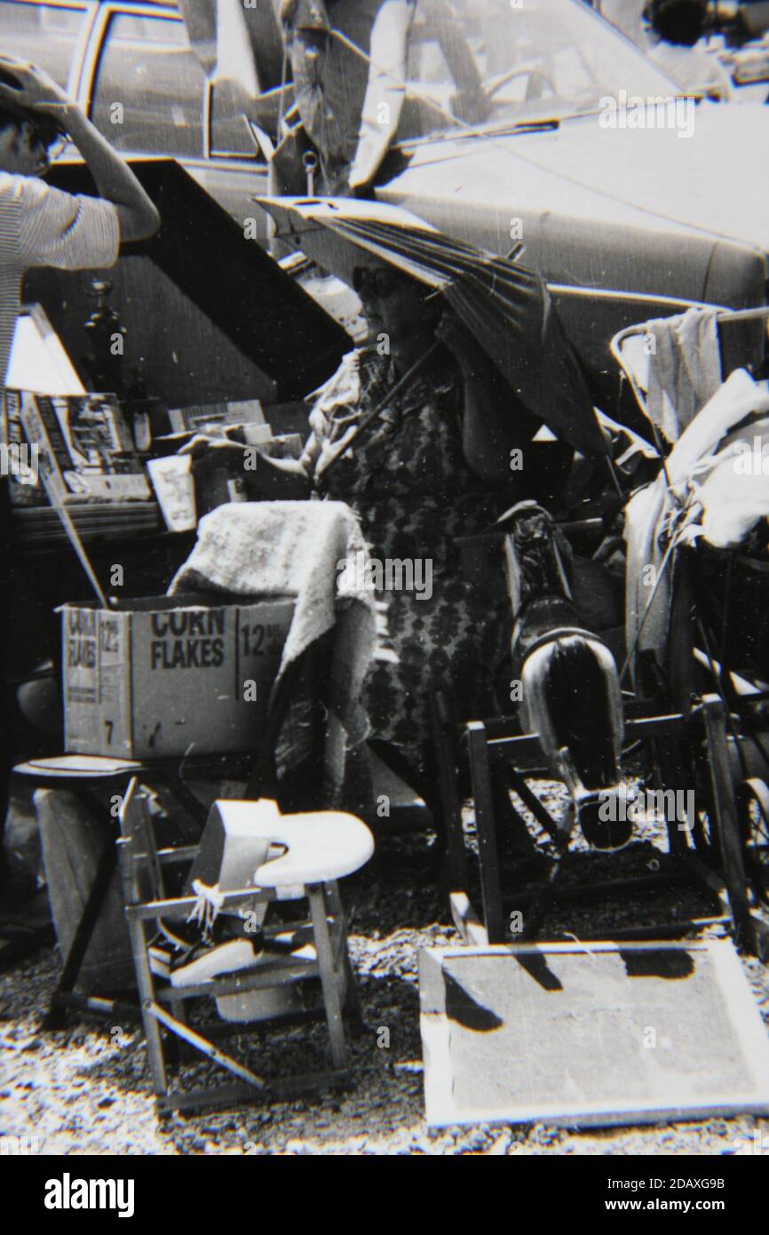 Fine 1970s vintage black and white photography of the hustle and bustle of an outdoor flea market swap o rama in the hot summer months. Stock Photo