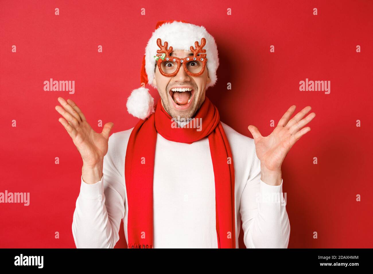Concept of christmas, winter holidays and celebration. Image of surprised and happy man looking amazed, wearing party glasses and enjoying new year Stock Photo