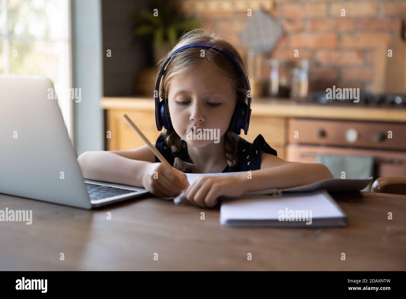 Thoughtful girl primary school pupil sitting by computer preparing report Stock Photo