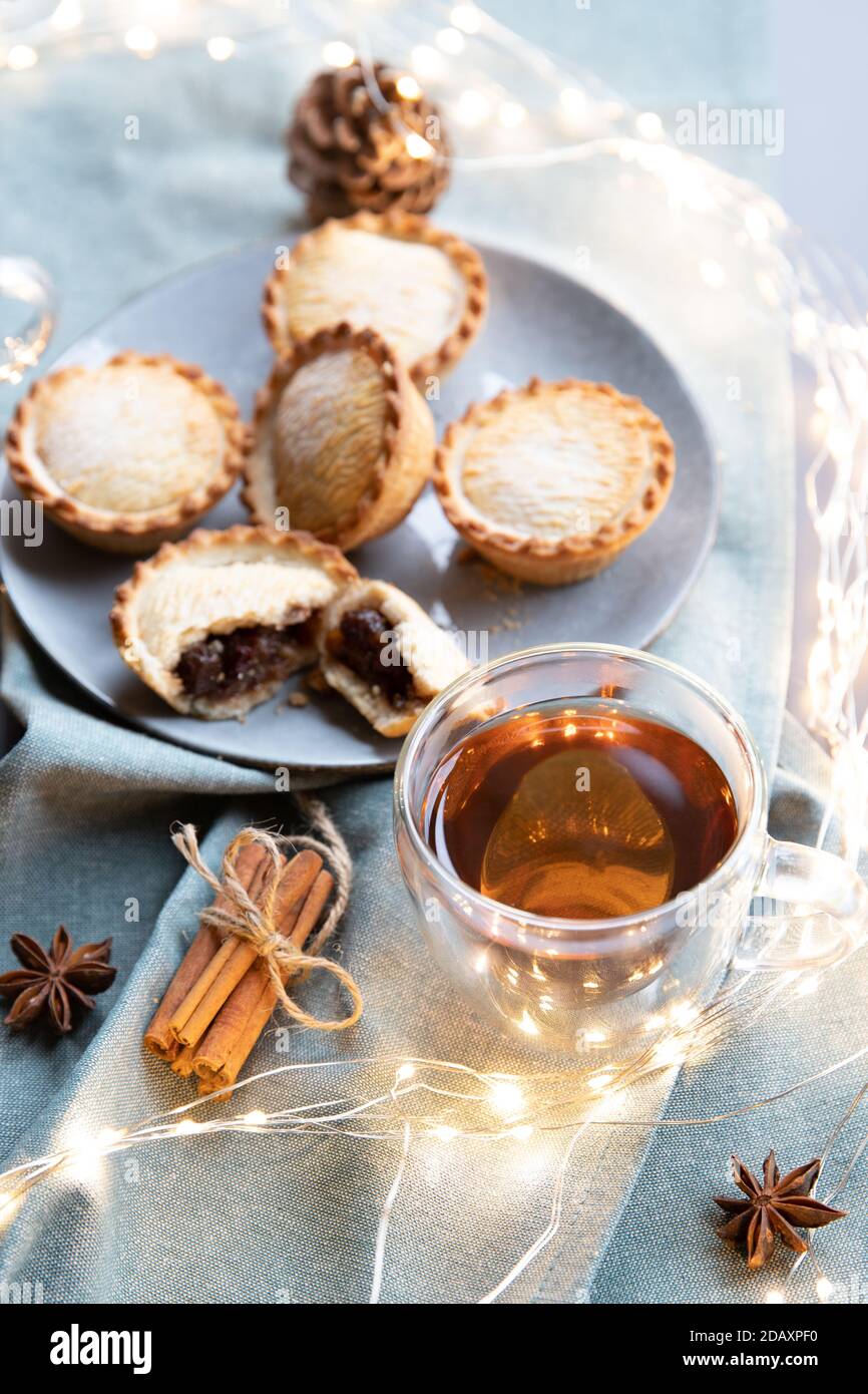 spiced black tea and sweet mince pies on a table with Christmas decoration, cinnamon sticks and anise stars. Stock Photo