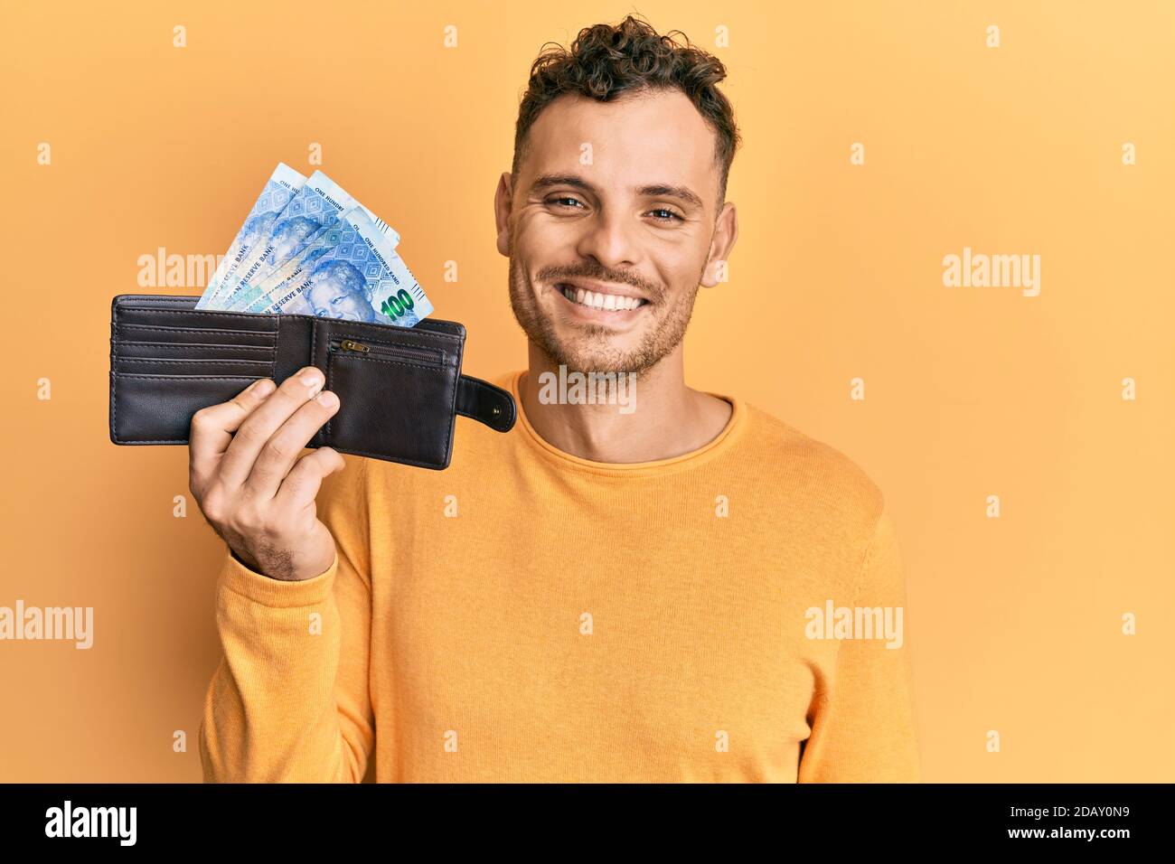 Handsome man with beard holding wallet with rand banknotes looking ...
