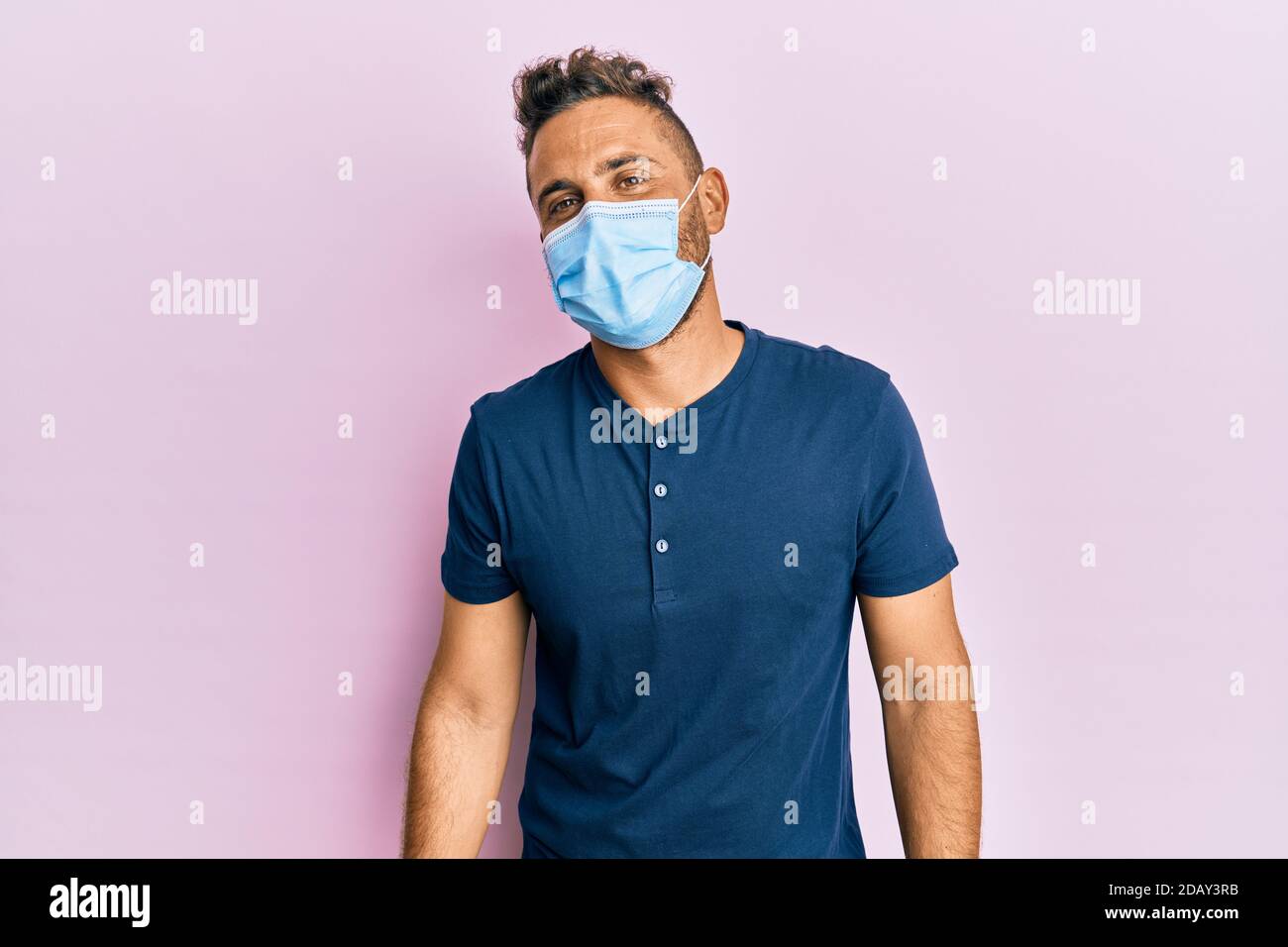Handsome man with beard wearing medical mask with a happy and cool ...