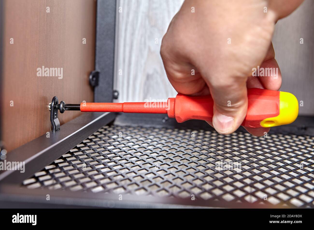 Worker tightens bolts while assembling flat pack furniture. Stock Photo