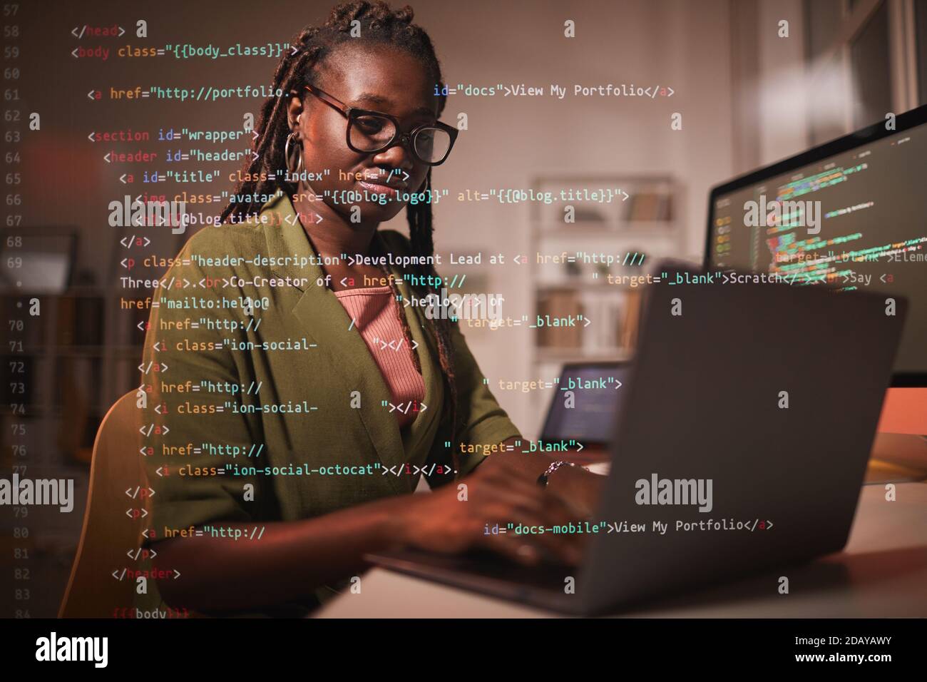 Portrait of contemporary African-American woman using laptop with computer code overlay, copy space Stock Photo