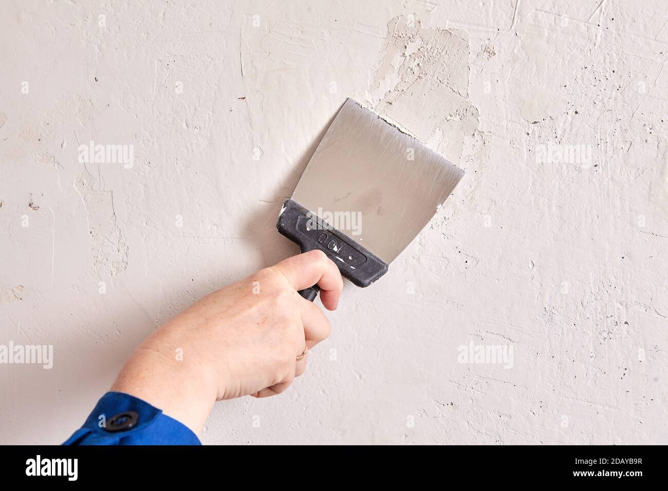 Handyman fills holes in wall with stucco and working tool Stock Photo