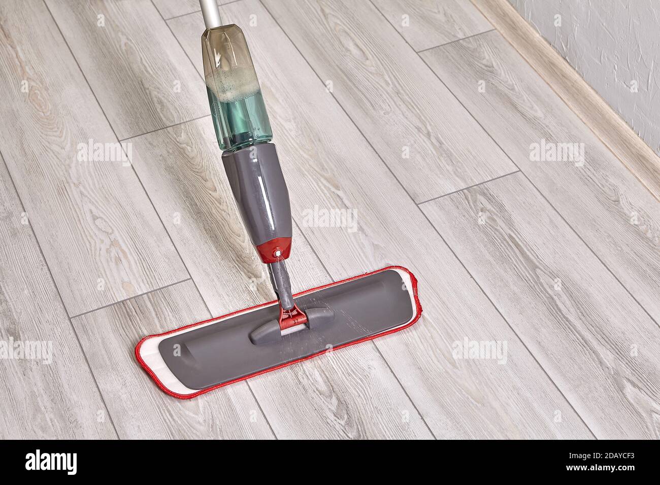 Cleaning lady cleans flat using mop with microfiber cloth and special liquid. Stock Photo