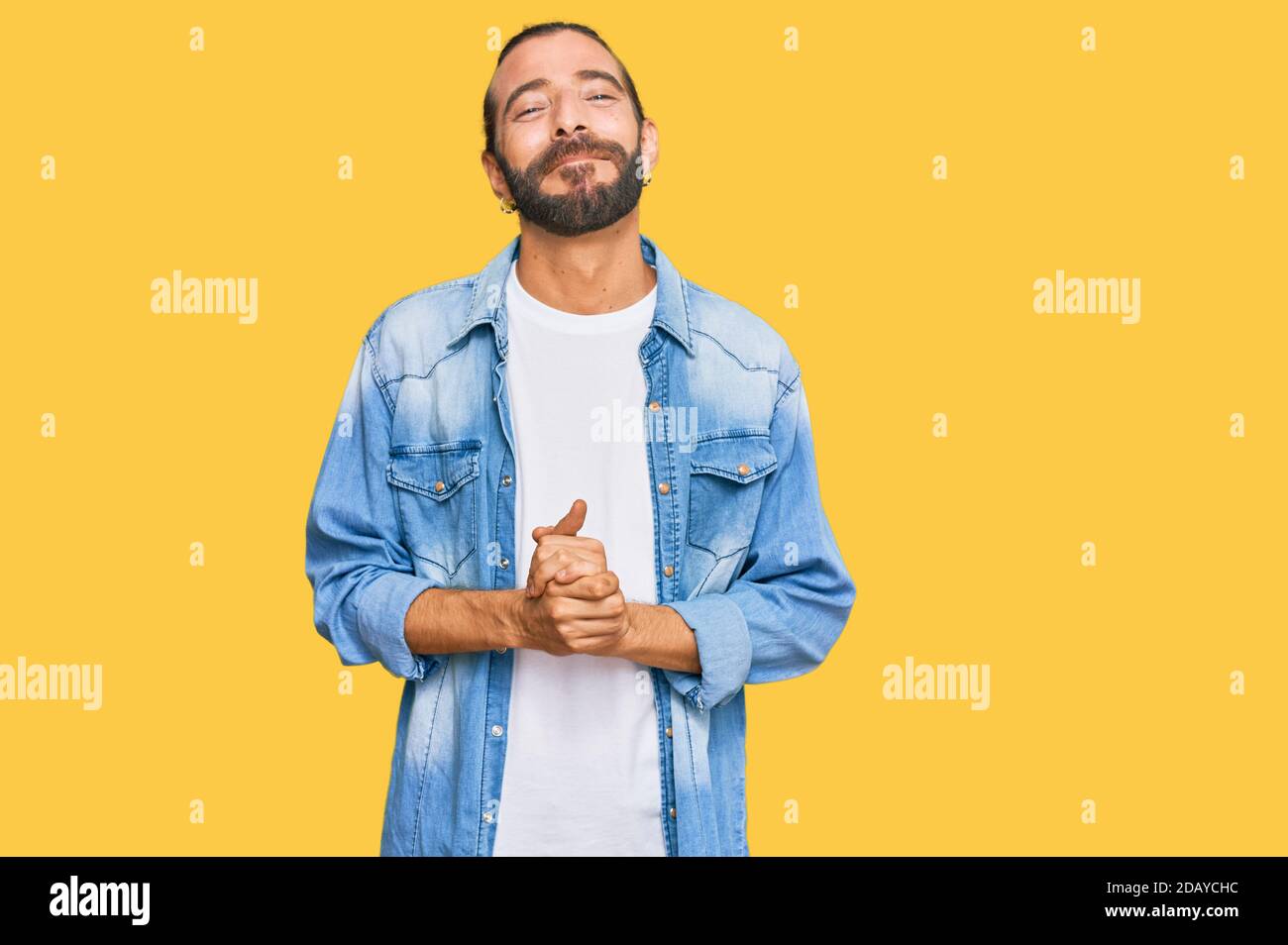 Attractive man with long hair and beard wearing casual denim jacket ...