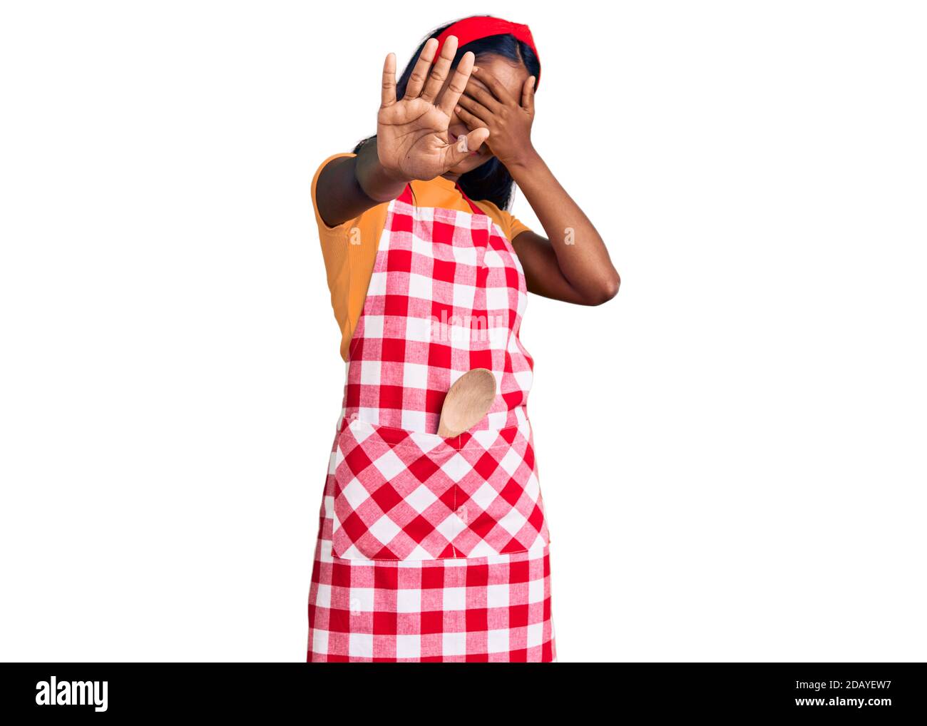Young indian girl wearing professional baker apron covering eyes with hands and doing stop gesture with sad and fear expression. embarrassed and negat Stock Photo