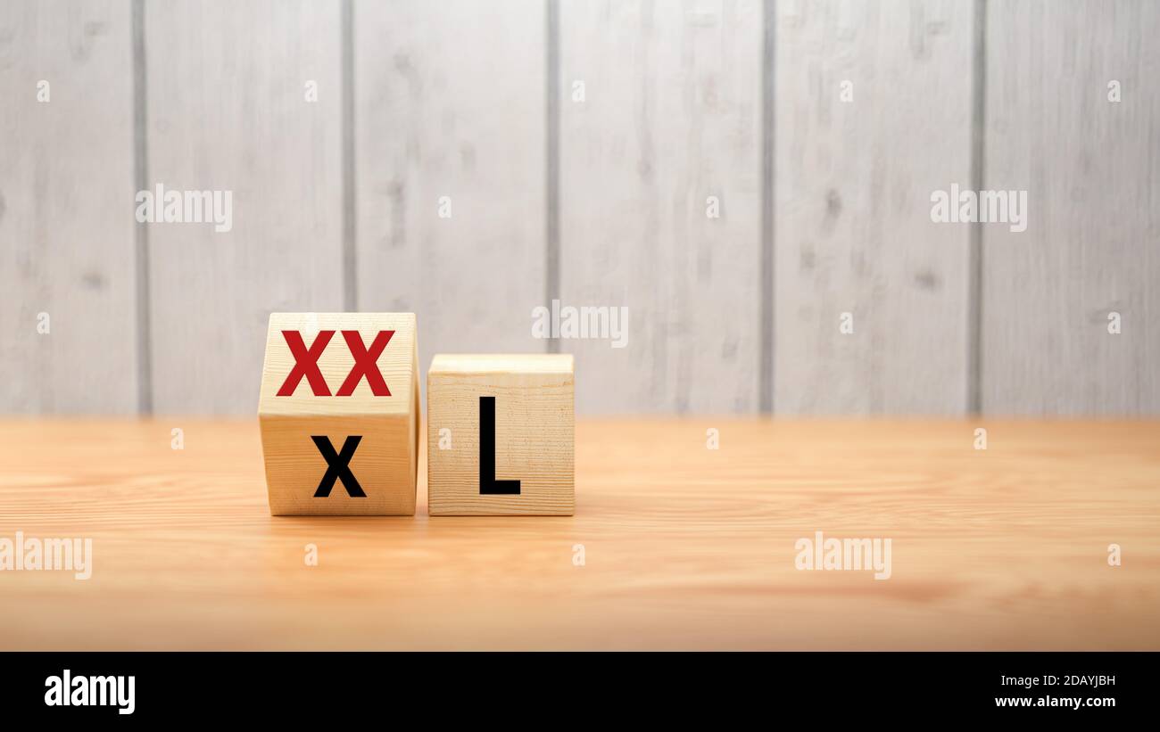cubes turning the message from XXL to XL on wooden background - 3d illustration Stock Photo
