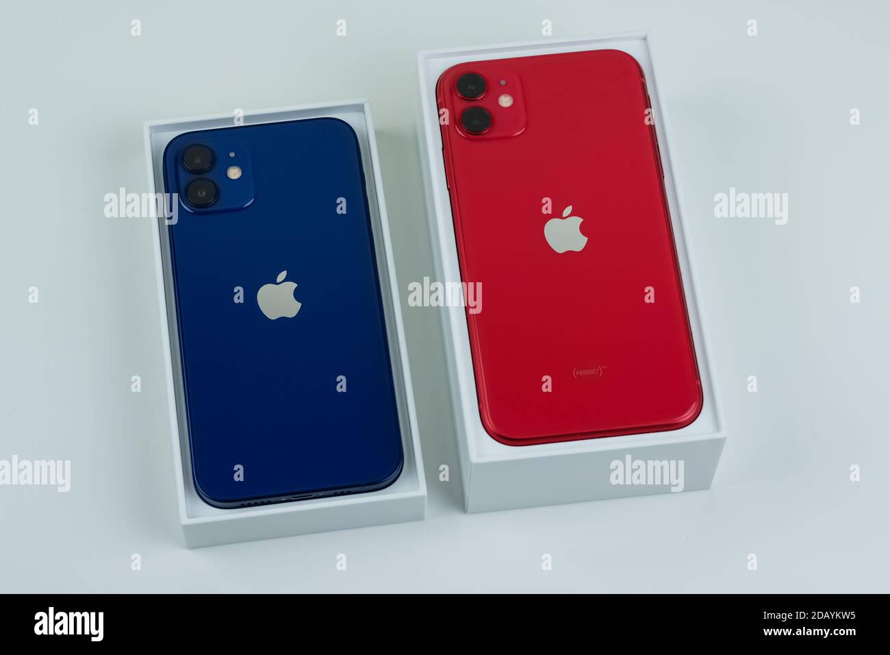 iPhone 12 in blue and iPhone 11 in red side by side. Stock Photo