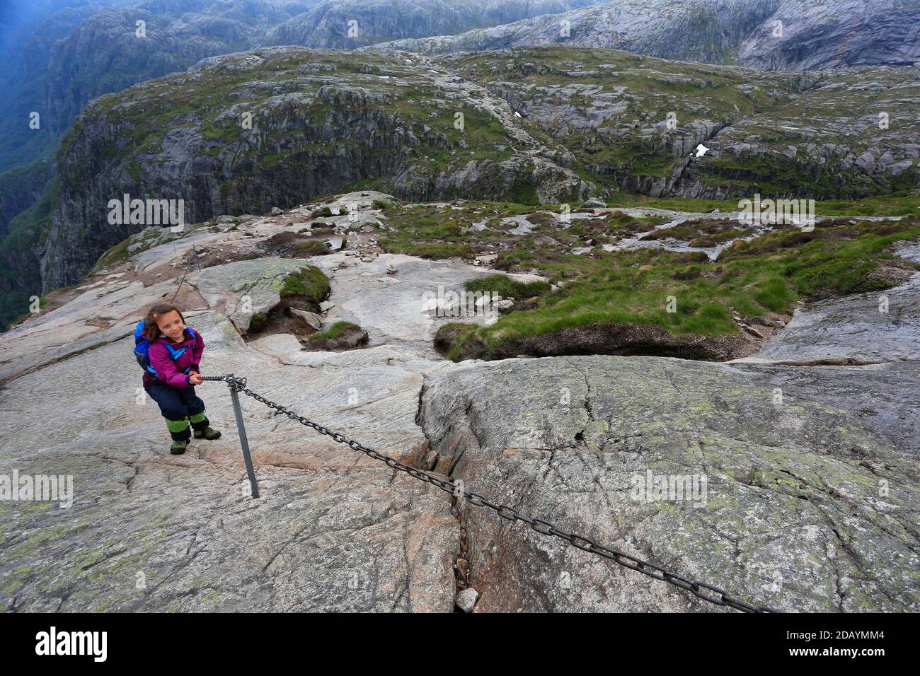 Young girl climbing on Kjerag Mountain trail over the Lysefjord in Norway Stock Photo