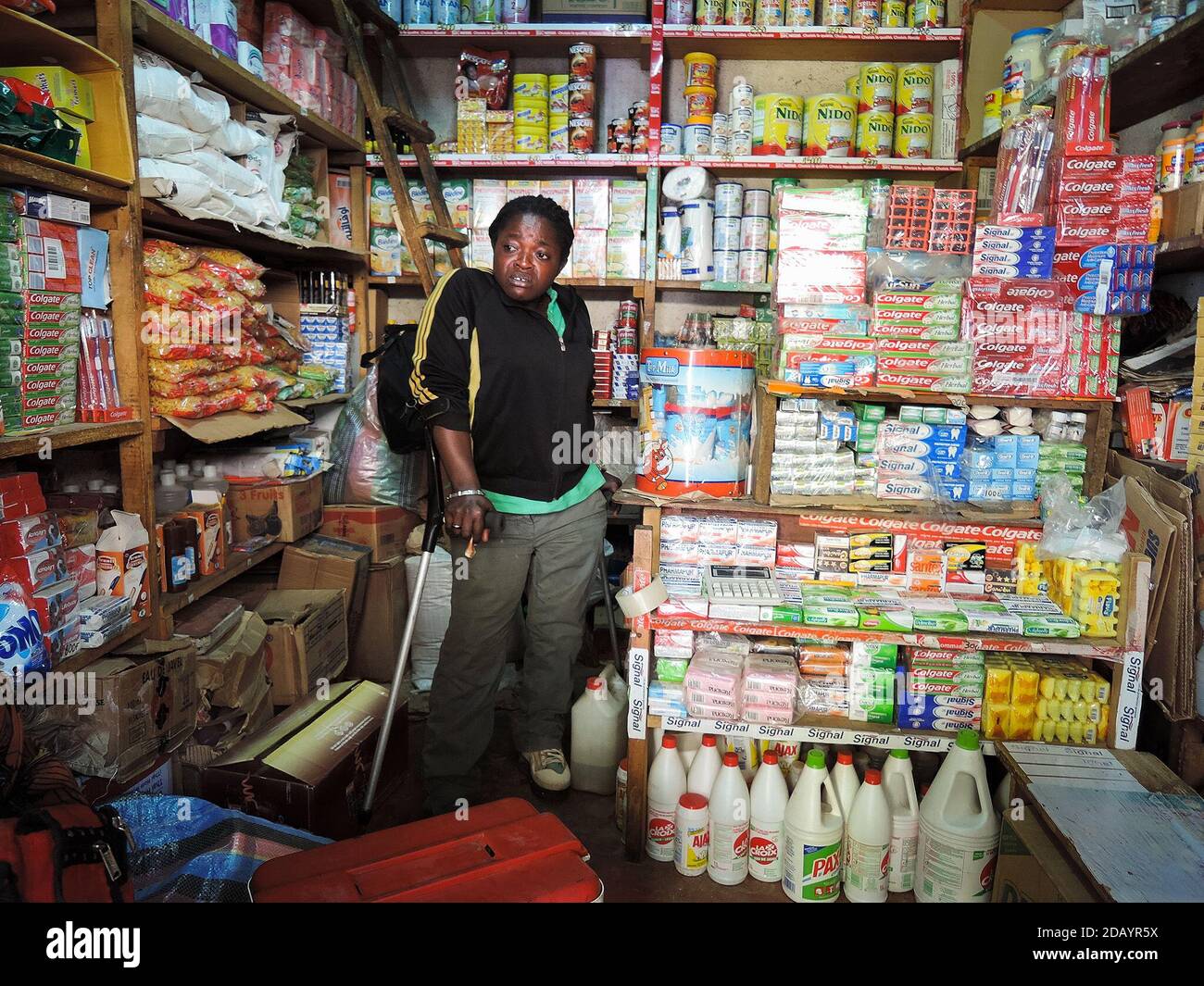 A woman uses a cane to walk around a market shop in Cameroon. Stock Photo