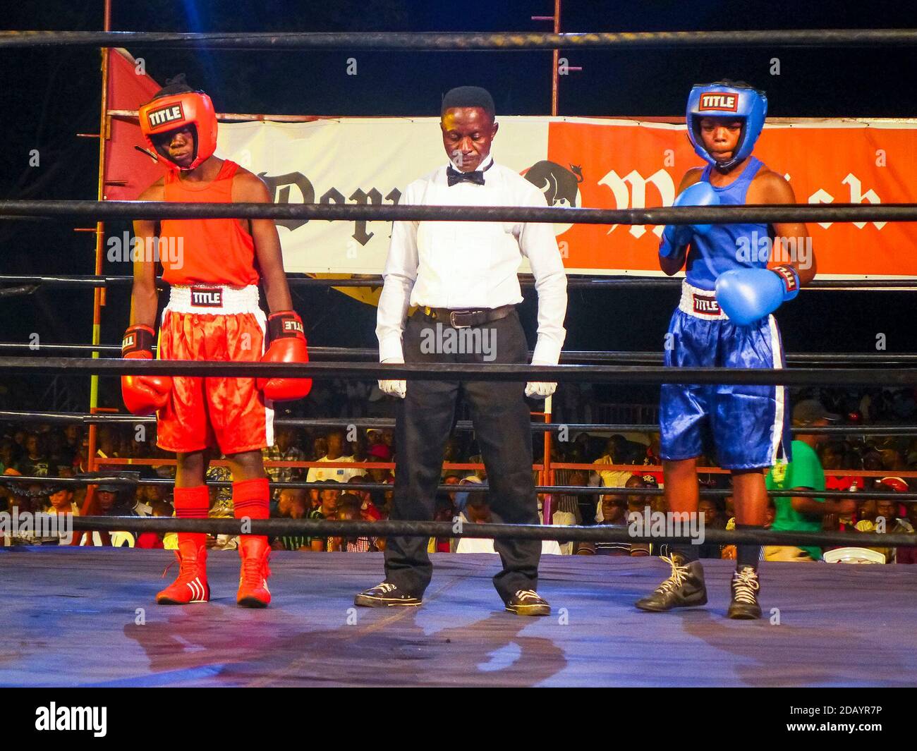 Two boxers wait in a boxing ring with a boxing referee in Kigali, Rwanda’s capital city. Stock Photo