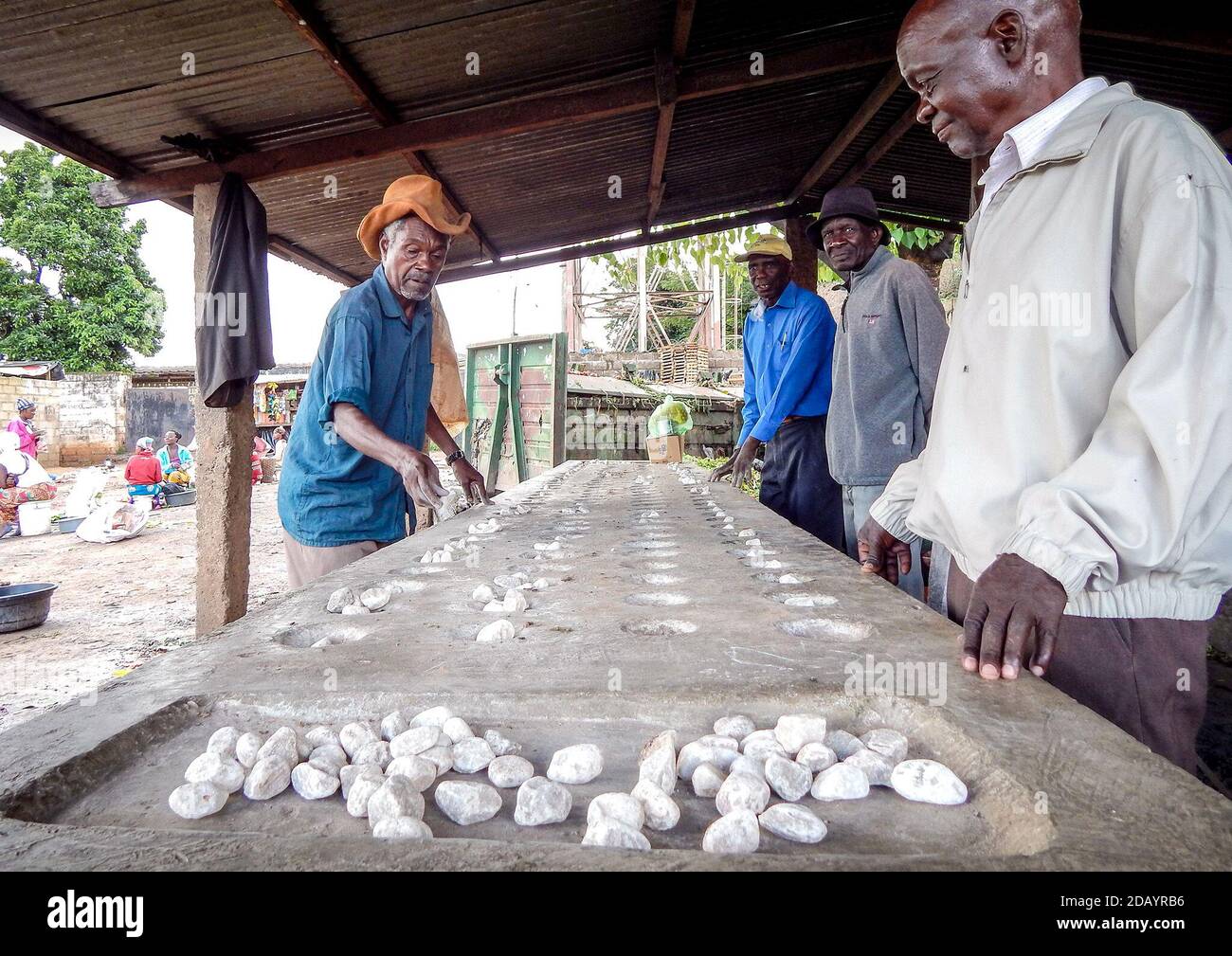 Aggrey Daka, 85, (CQ) left, plays a traditional Zambian game known as Nsolo (similar to mancala) with his fellow elders on Jan 25, 2017 at Mtendere Market shelter, (CQ) in Lusaka, the capital city of Zambia. Daka, who stays at the shelter, says that playing the game reminds them of playing the game as young men and of the “good old days”.  (Prudence Phiri, GPJ Zambia) Stock Photo