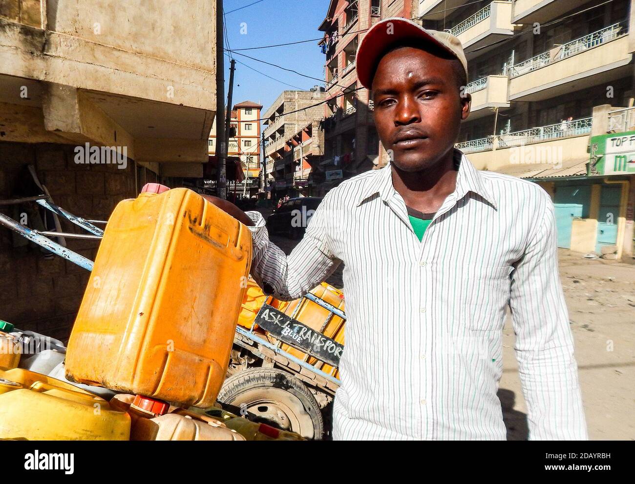 Alfred Mutua, 26, waits for customers in the Umoja One area in Nairobi County, Kenya, where he sells water. Stock Photo