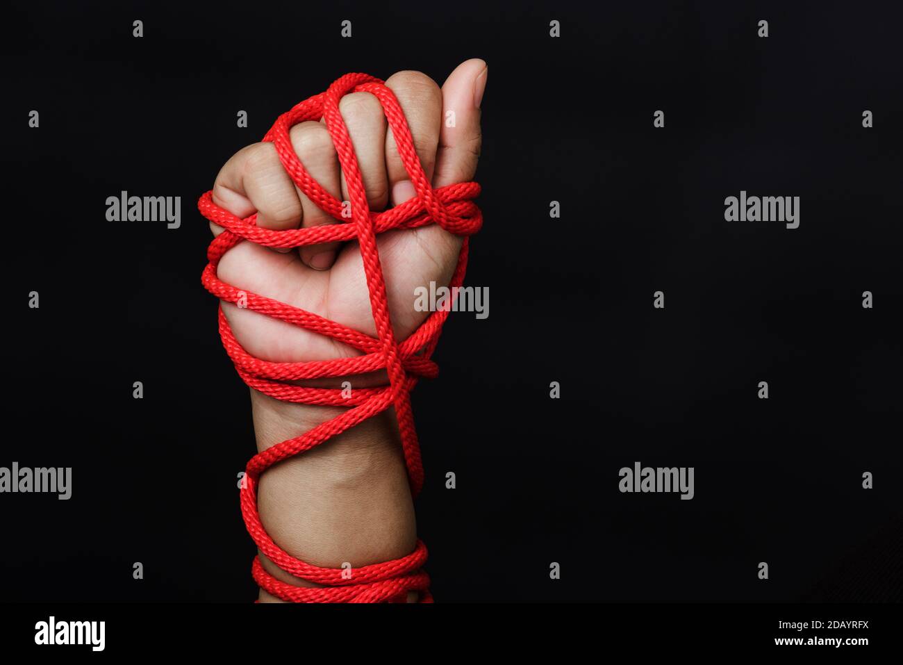 Woman hand tied up with rope on black background, Human trafficking and abuse, International Human Rights day Stock Photo