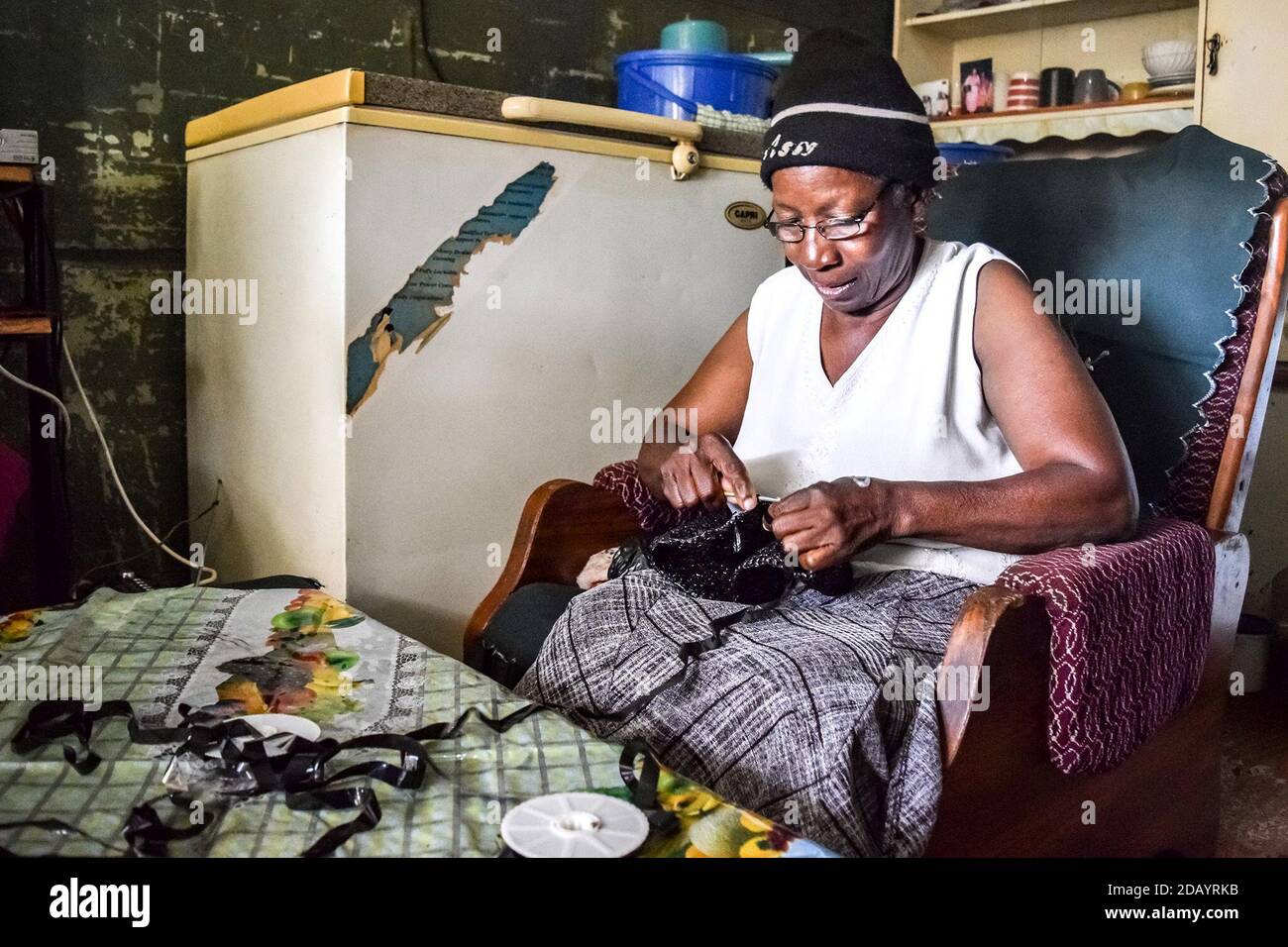 Sarah Hungwe, 67, crochets a bag using old cassette tapes as a part of Friendship Bench, a project to help depression in Harare, Zimbabwe. Stock Photo