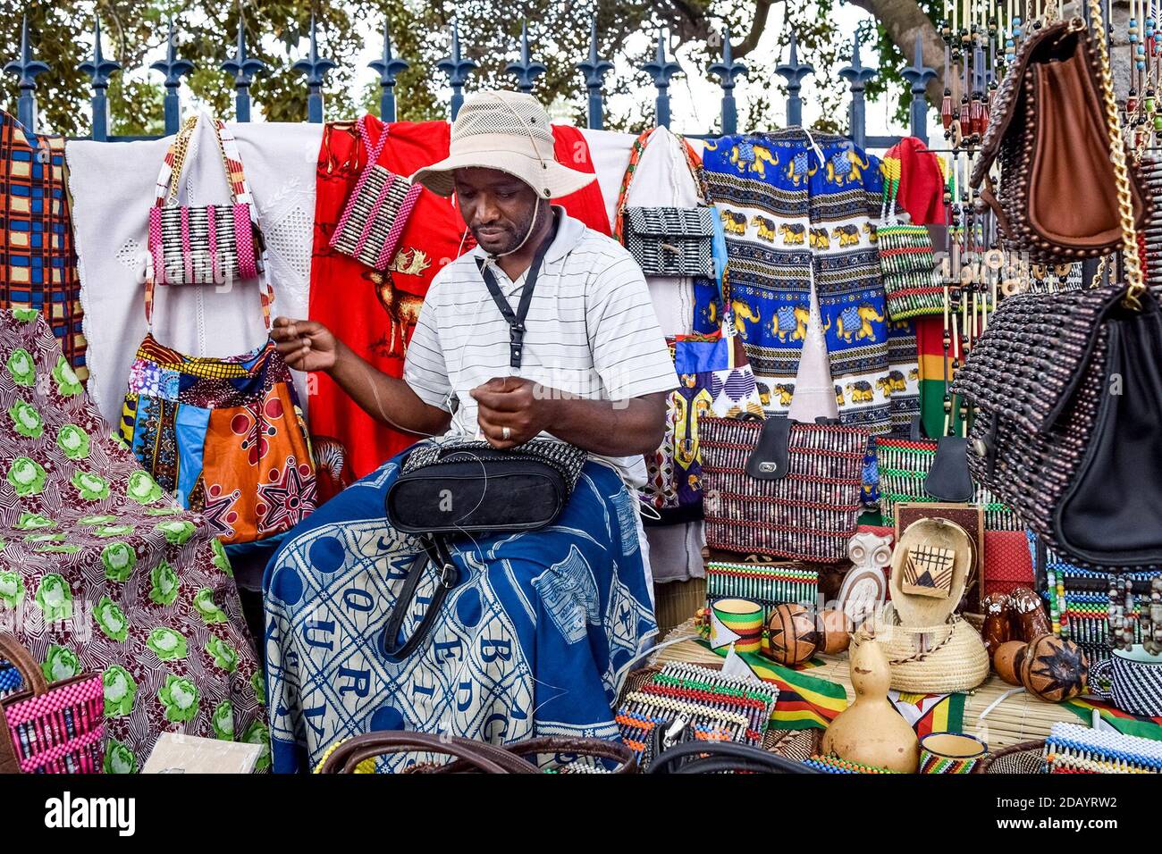 Street vendor Lionel Thabo Mpofu, 37, makes a beaded bag at his stand on Fife Street in Bulawayo, Zimbabwe Stock Photo
