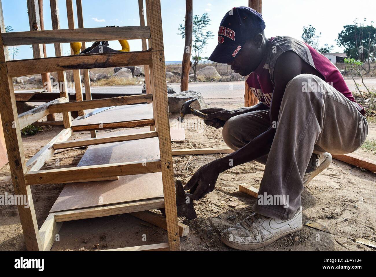In Hopley Farm, Harare Province, Zimbabwe, Maxwell Dzawanda, 37, builds a wardrobe out of wood planks. Stock Photo