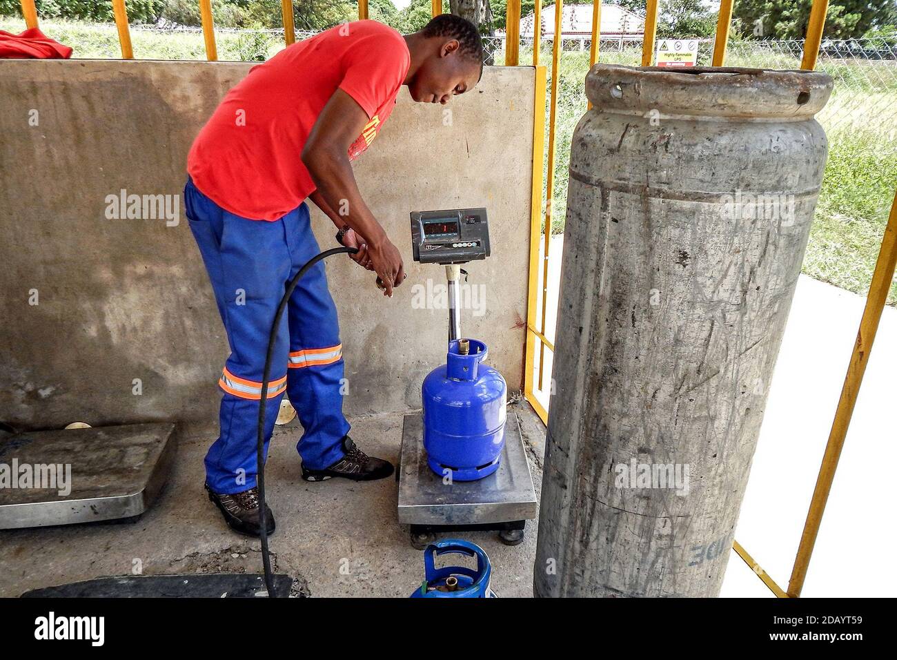 Tadiwanash Chakata, a member of the NeedEnergy delivery team, refills and weighs a gas cylinder for a client order in Bradfield, Bulawayo, Zimbabwe Stock Photo