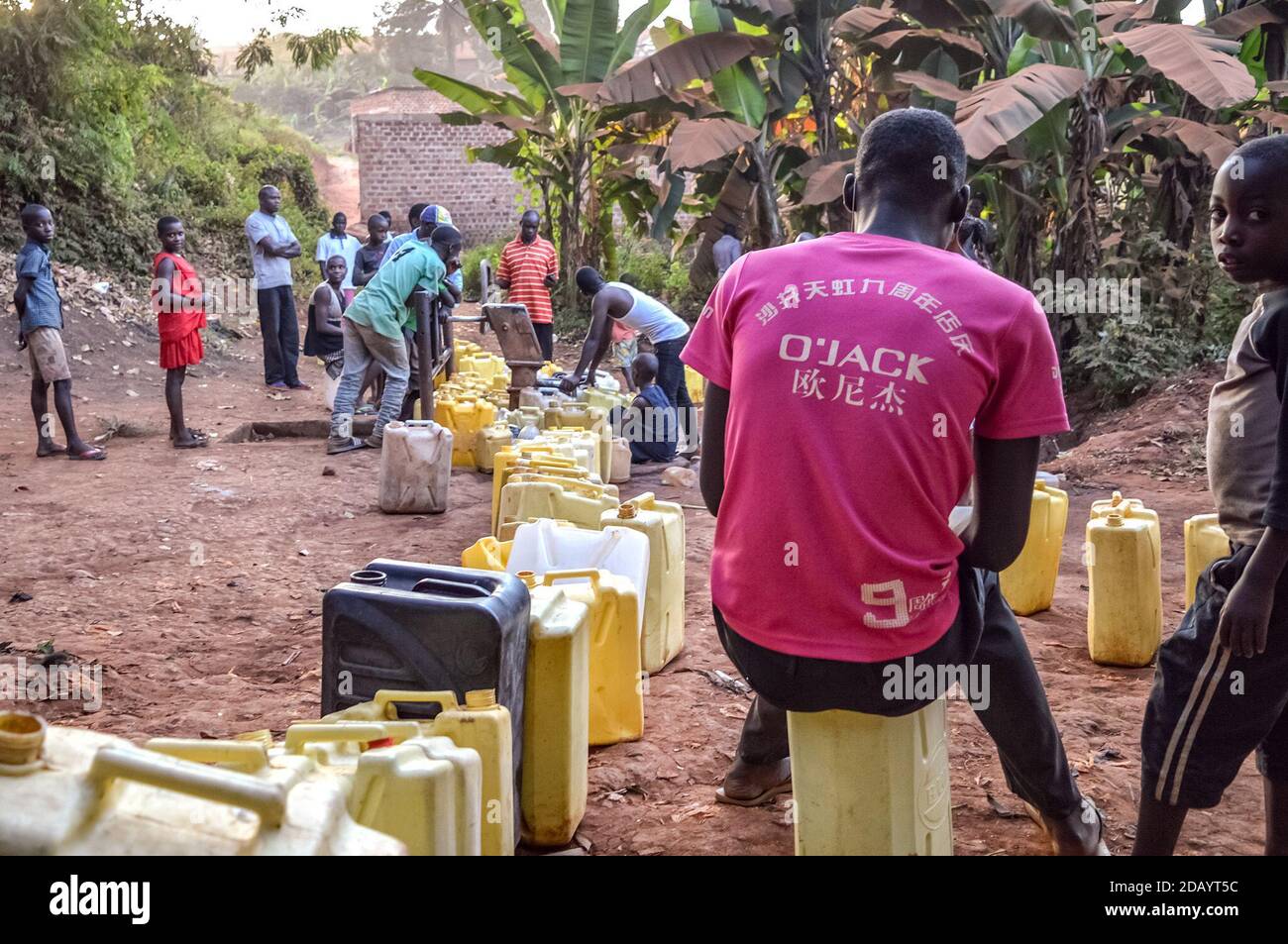 Residents of Nsumbi village line up their jerrycans to fetch water from a bore hole in a neighboring district. Stock Photo