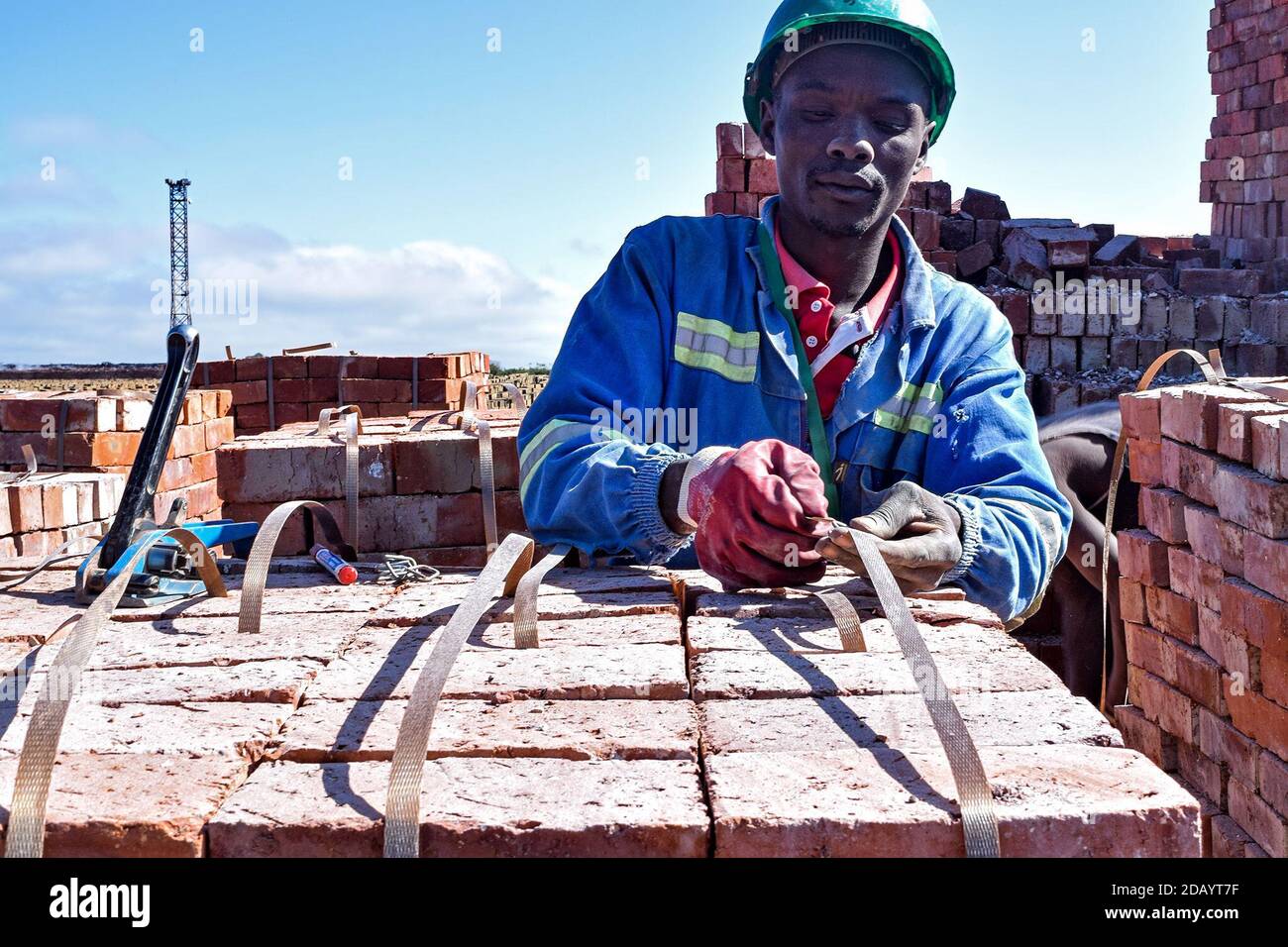 Admire Chipango straps bundles of bricks together, using plastic strapping from recycled brown bottles. Stock Photo