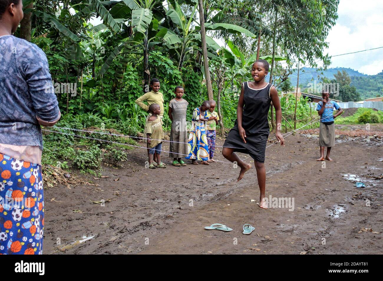 In Kibaya village in Rwanda’s Rubavu District, Denise Feza (center) plays a homemade game that involves jumping in the middle of a long rope wrapped around the hips of two friends. Stock Photo