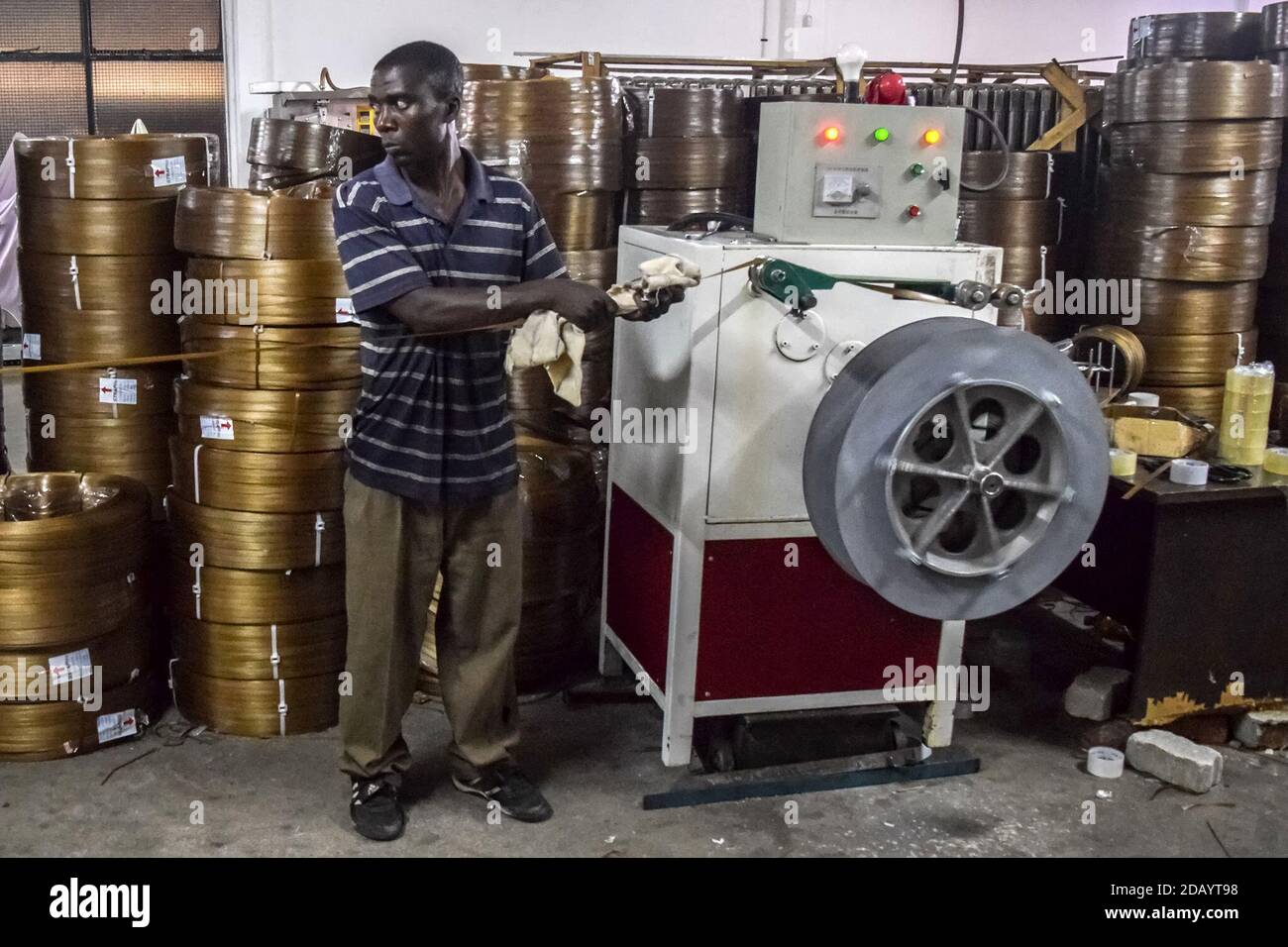 Tsungisai Magutu uses a rolling machine to create rolls of brown plastic strapping. Stock Photo