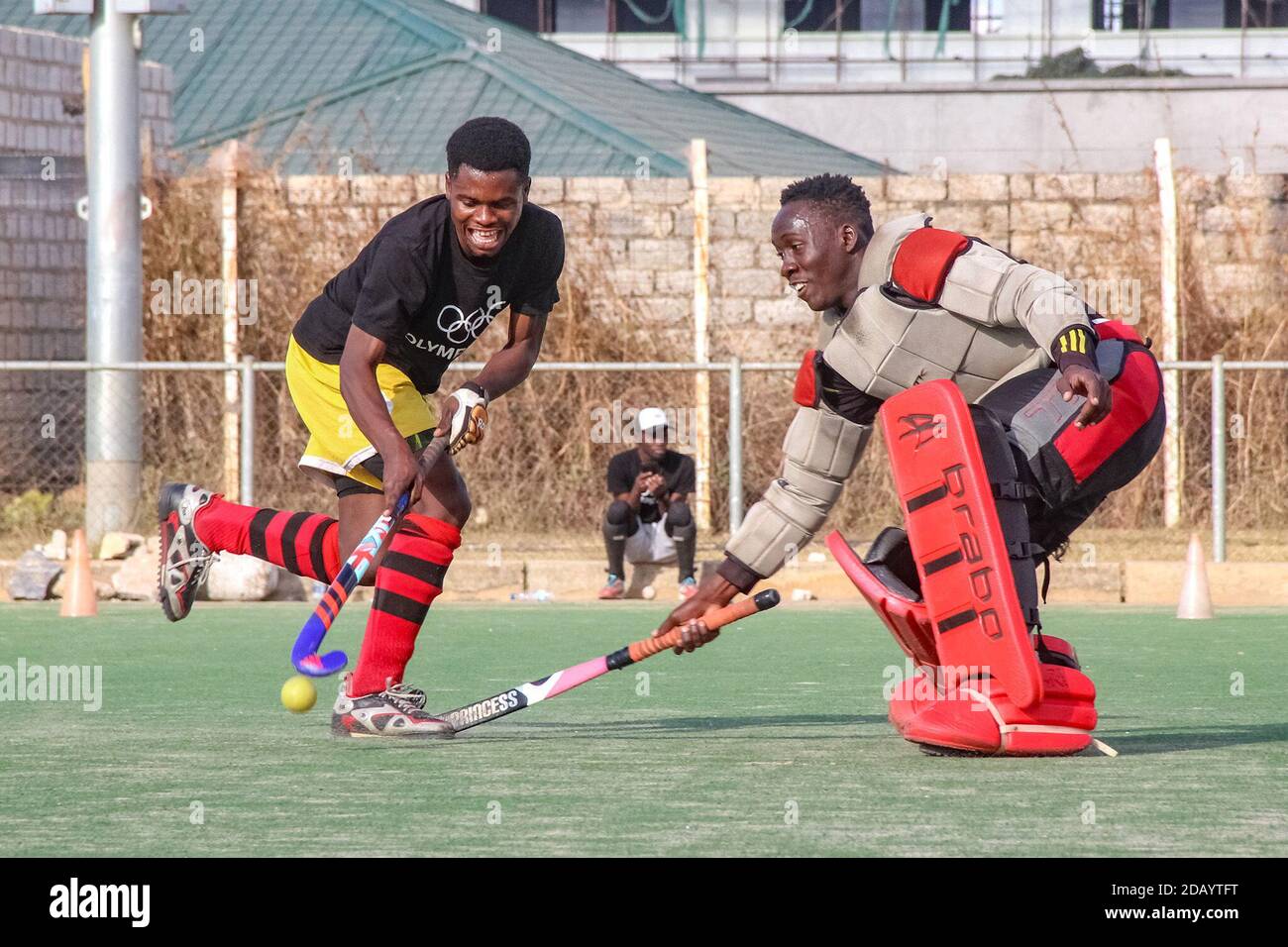 Samson Tembo (left) dribbles the ball around goalkeeper Richard Lungu, who attempts to defend the goal during a practice hockey match at the Olympic Youth Development Centre, a sports venue for young people in Lusaka, Zambia. Stock Photo
