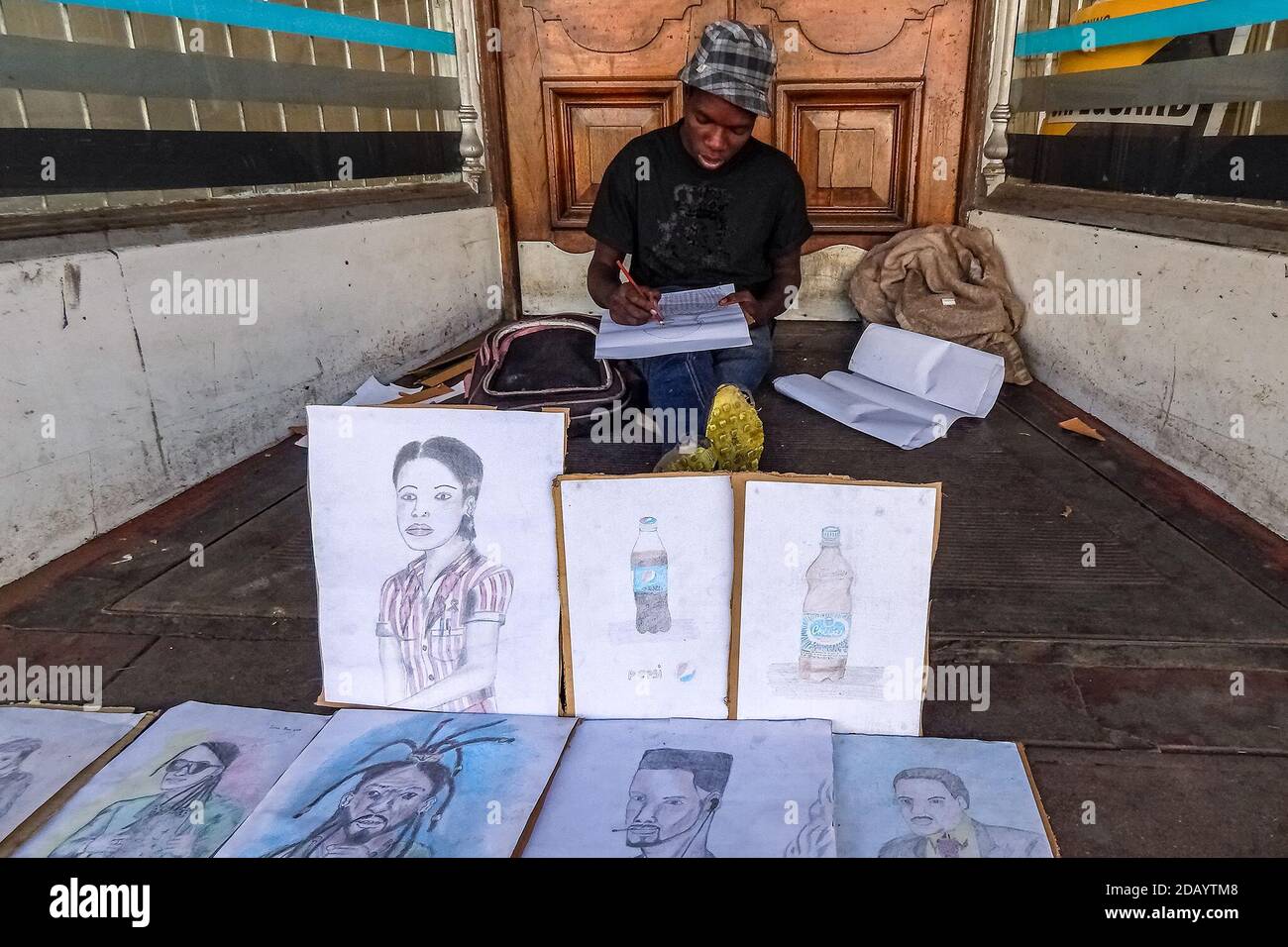 Learnmore Sibanda, 18, sits on the sidewalks of Bulawayo, Zimbabwe, sketching and selling portraits for $1 each. Stock Photo
