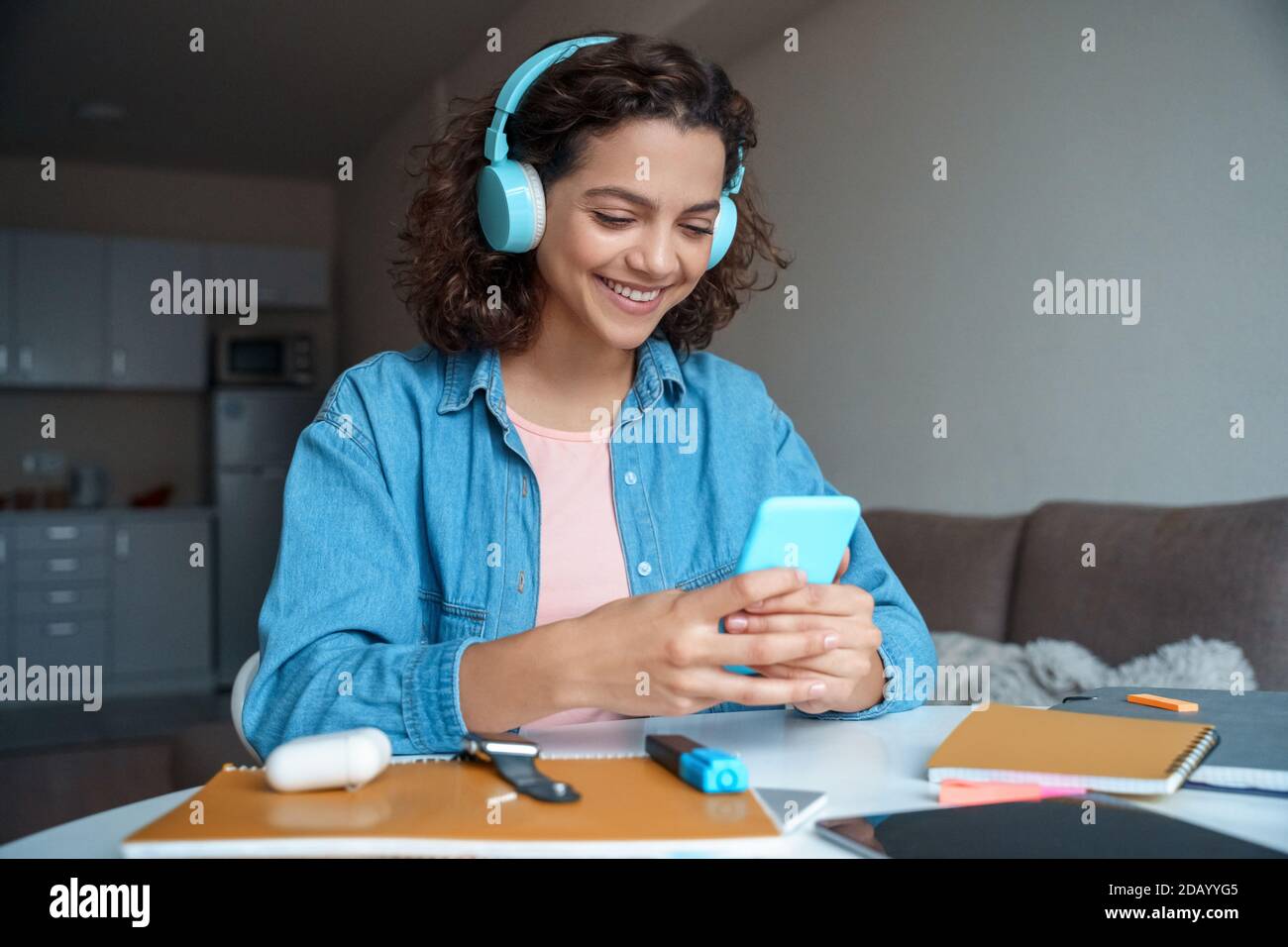 Hispanic young woman in earphones using smartphone app. Stock Photo