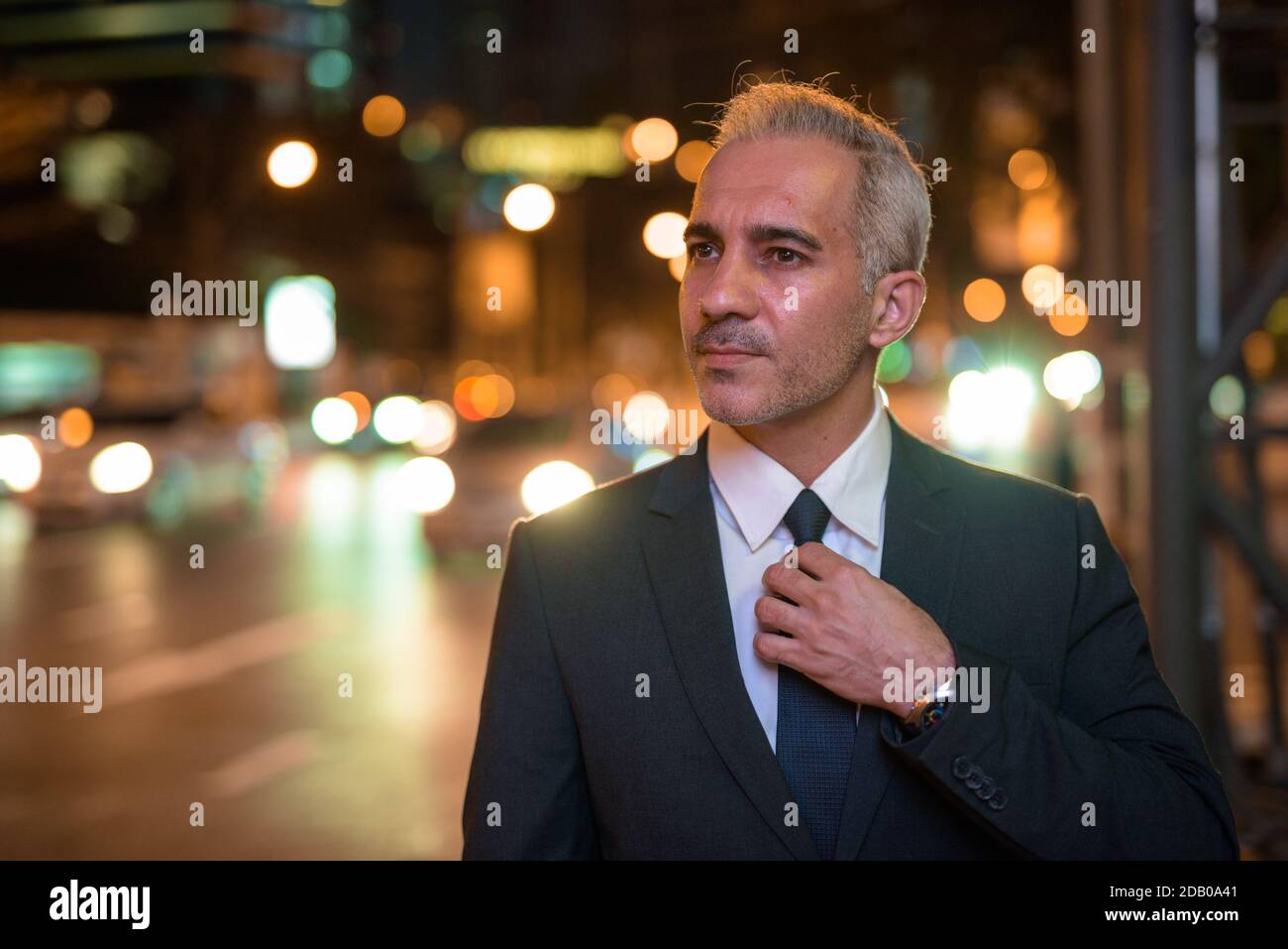 Portrait of handsome businessman wearing suit in city at night while ...