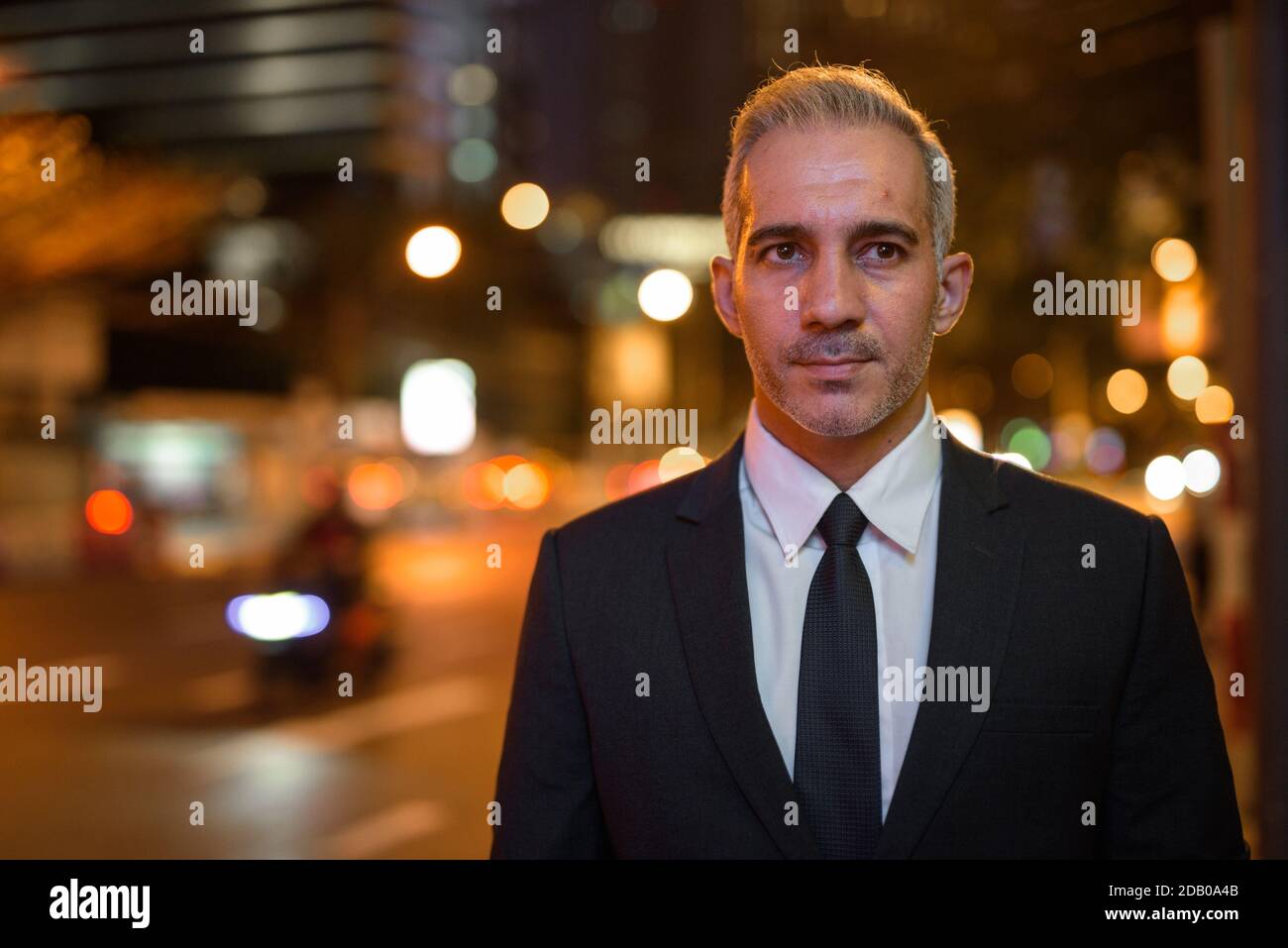 Portrait of handsome businessman wearing suit in city at night while ...