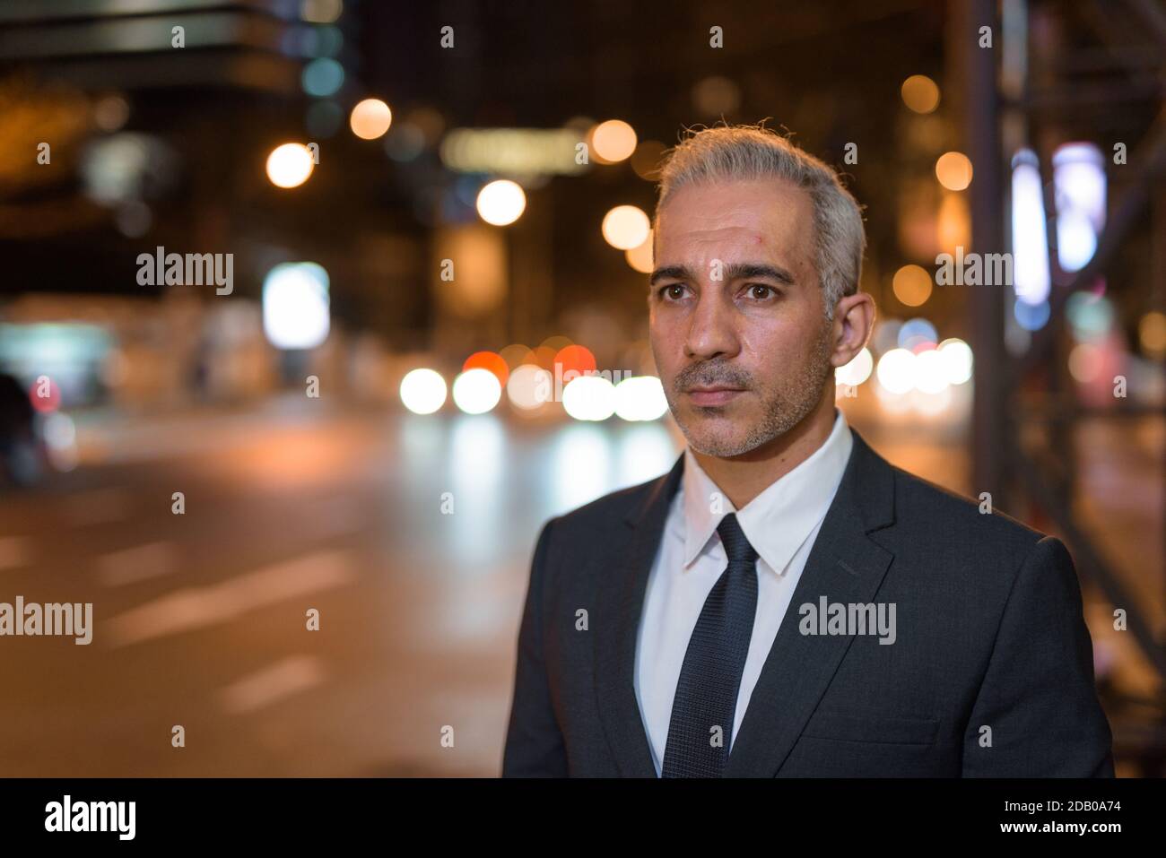 Portrait of handsome businessman wearing suit in city at night Stock ...