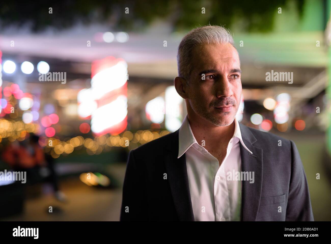 Portrait of handsome businessman wearing suit in city at night while ...