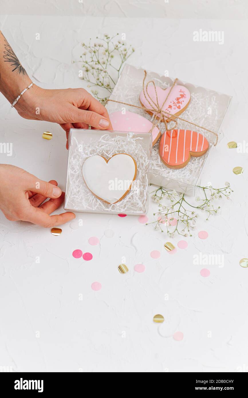 Hands holding box casing with scarlet heart shaped cookie Stock Photo