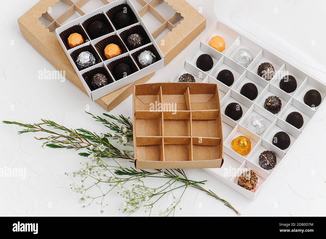 Fancy wrapped chocolate candies in sectioned boxes next to empty ones Stock Photo