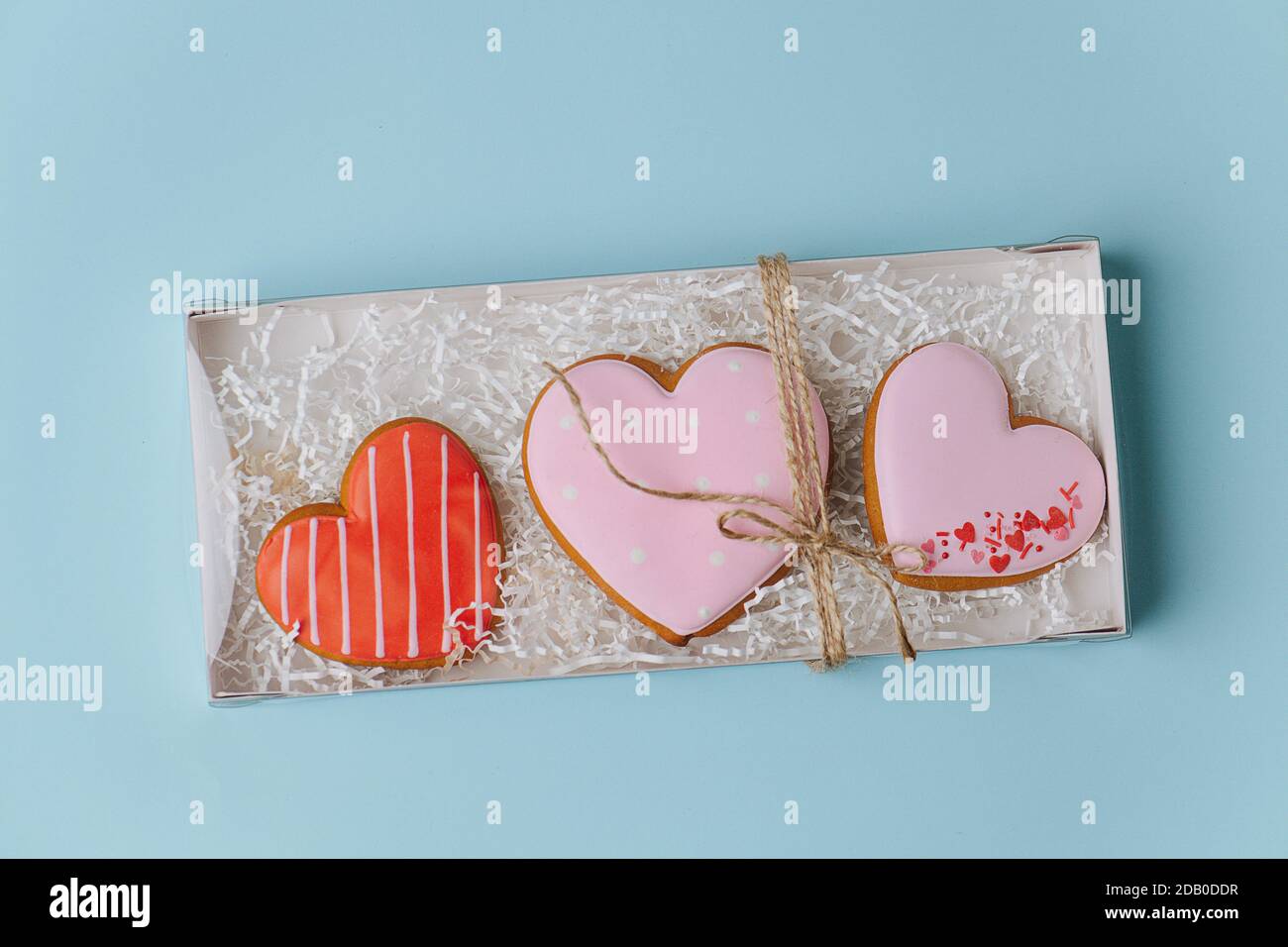 Big scarlet heart cookies in a box casing with filling paper. Top view Stock Photo