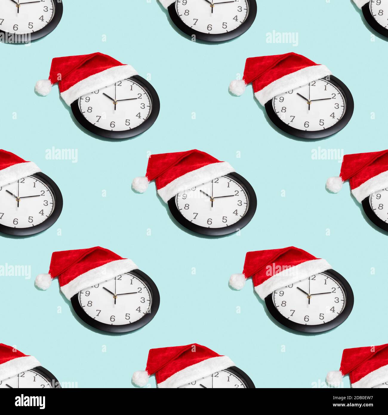 Seamless pattern christmas composition with classic analog clock in red christmas cap isolated on blue background, top view, flat lay Stock Photo