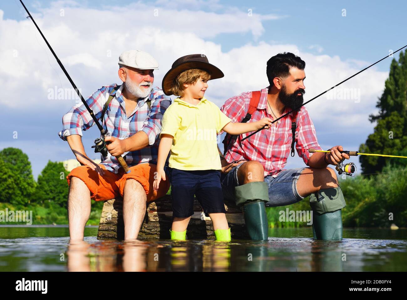 Funny happy little kid fishing on weekend. A fisherman boy stands in the  lake with a fishing rod and catches fish. Stock Photo