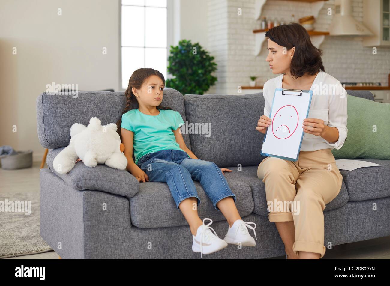 Child psychologist having therapy session with little girl discussing and portraying emotions Stock Photo