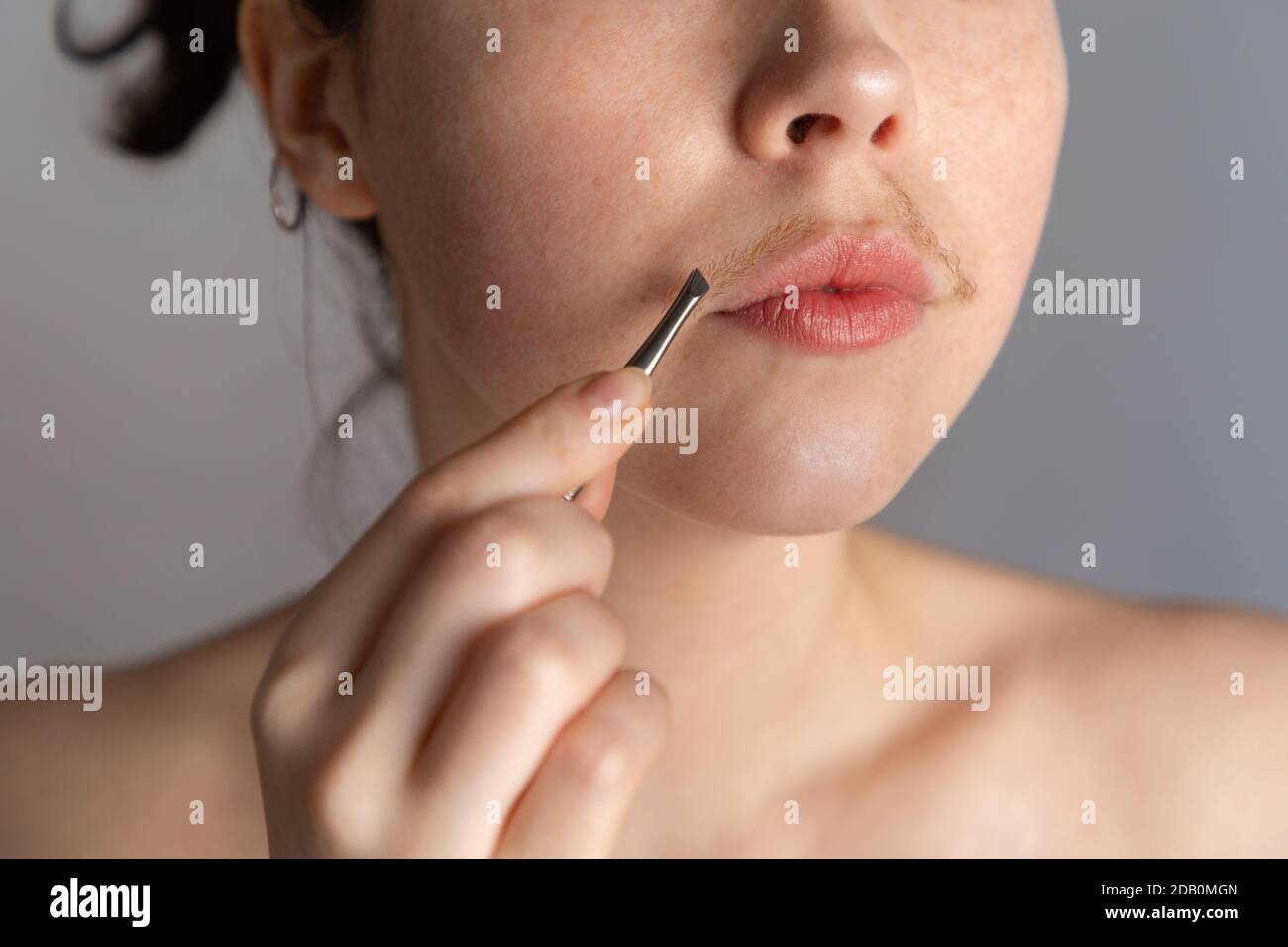 A young woman with a mustache tries to remove the hair over her lip with  tweezers. The concept of getting rid of unwanted facial hair. Close up  Stock Photo - Alamy